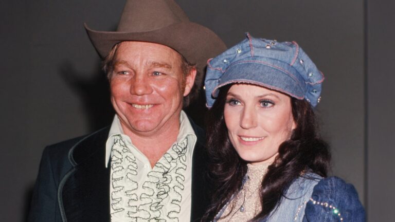 Loretta Lynn and Oliver "Mooney" Lynn pose arm-in-arm in a classic 1970s photo, capturing their wild, loving 48-year marriage filled with chaos, infidelity, abuse, and enduring devotion.
