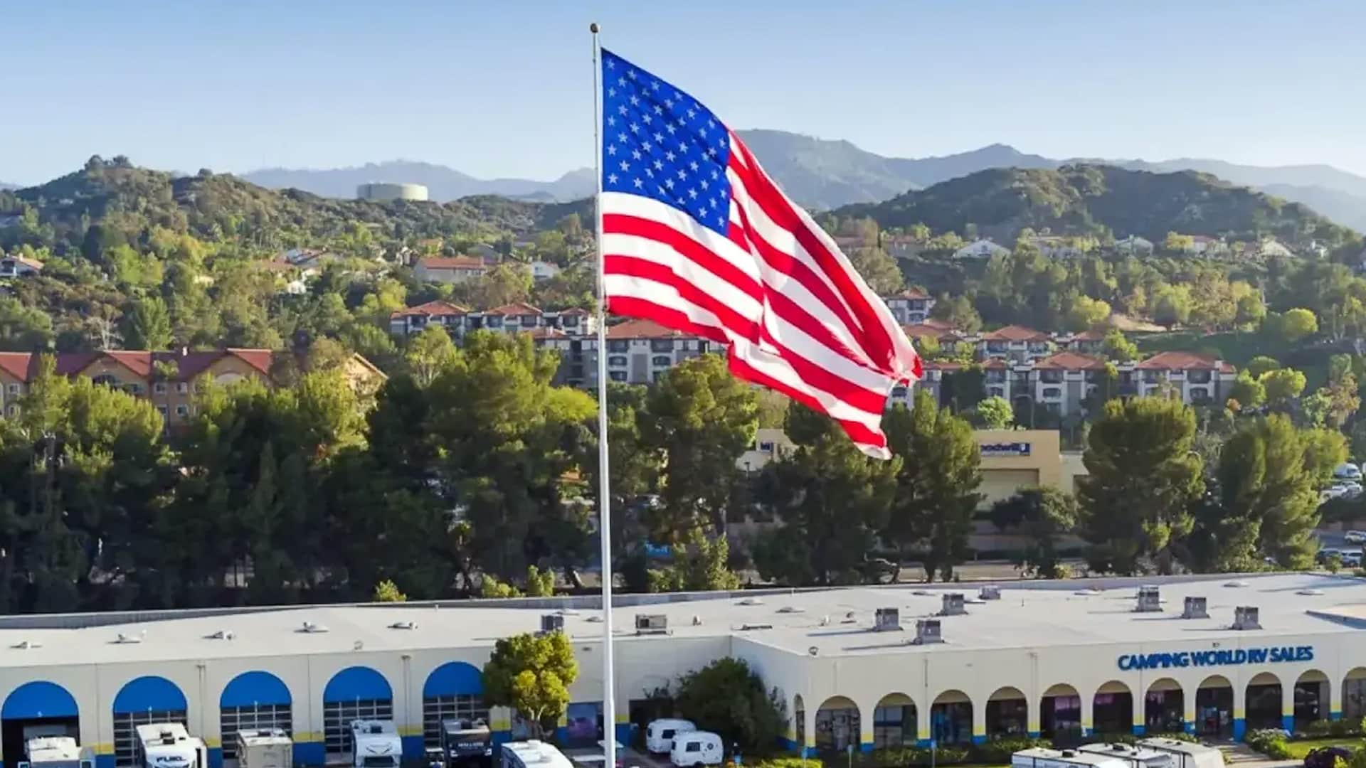 A massive American flag waves proudly above a Camping World RV Sales store in North Carolina, symbolizing the patriotism behind CEO Marcus Lemonis' decision to close the store rather than remove the flag.