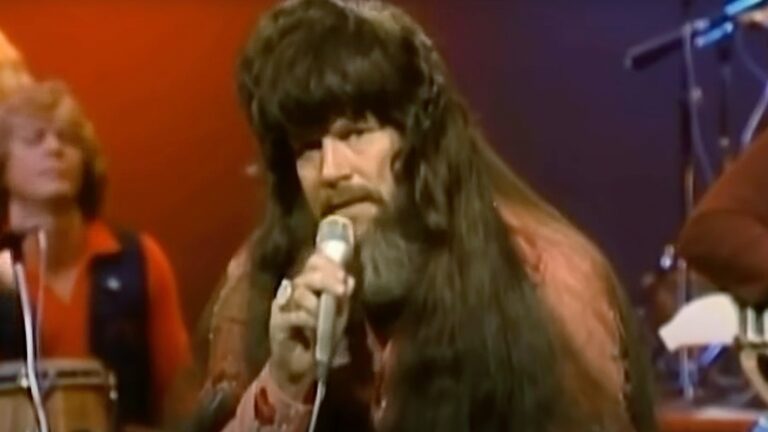 David Allan Coe performed onstage in the early 1980s with long hair and outlaw attitude, singing “Tennessee Whiskey” with gritty intensity.