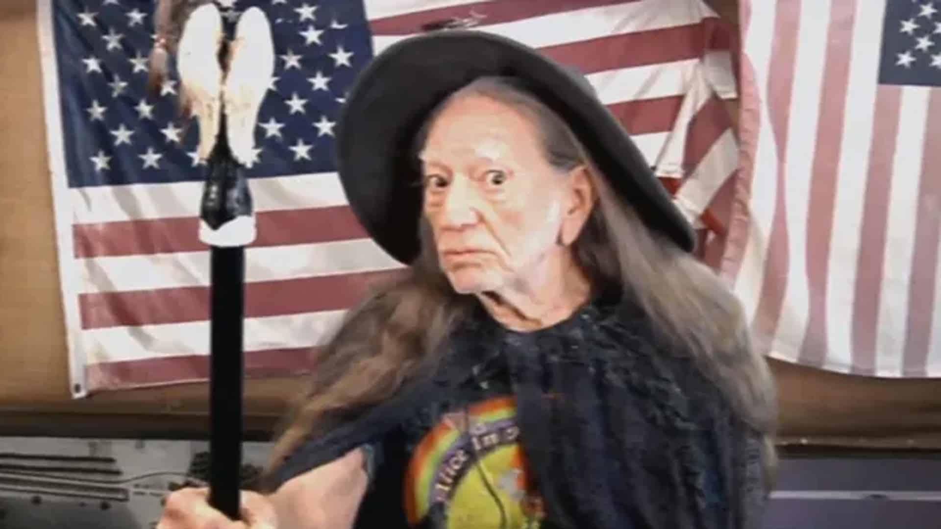 Willie Nelson dressed as Gandalf with a long white beard and wizard hat, holding a staff and delivering lines in a mock audition for The Hobbit.