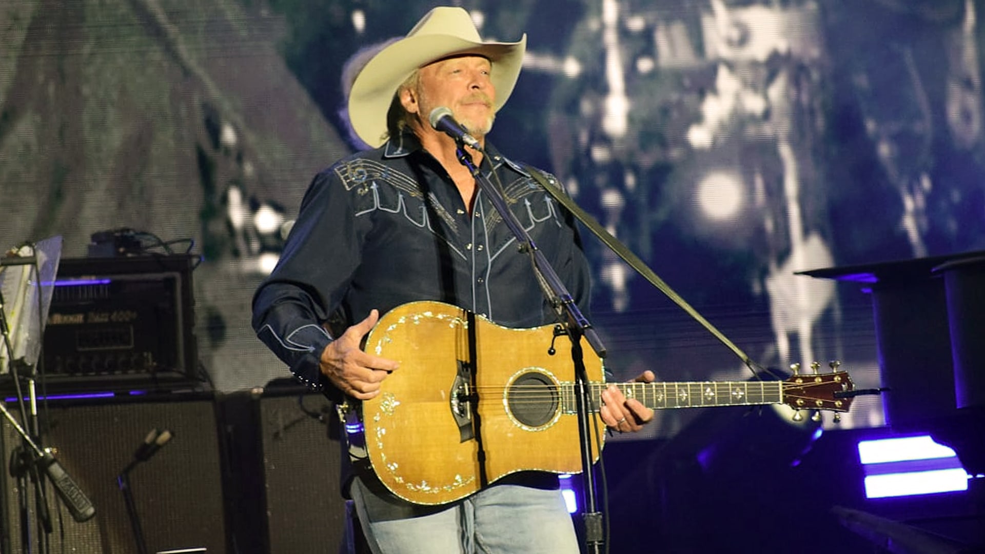 Alan Jackson performs on stage in a cowboy hat with his guitar, moments before announcing his final tour show and a last farewell concert in Nashville.