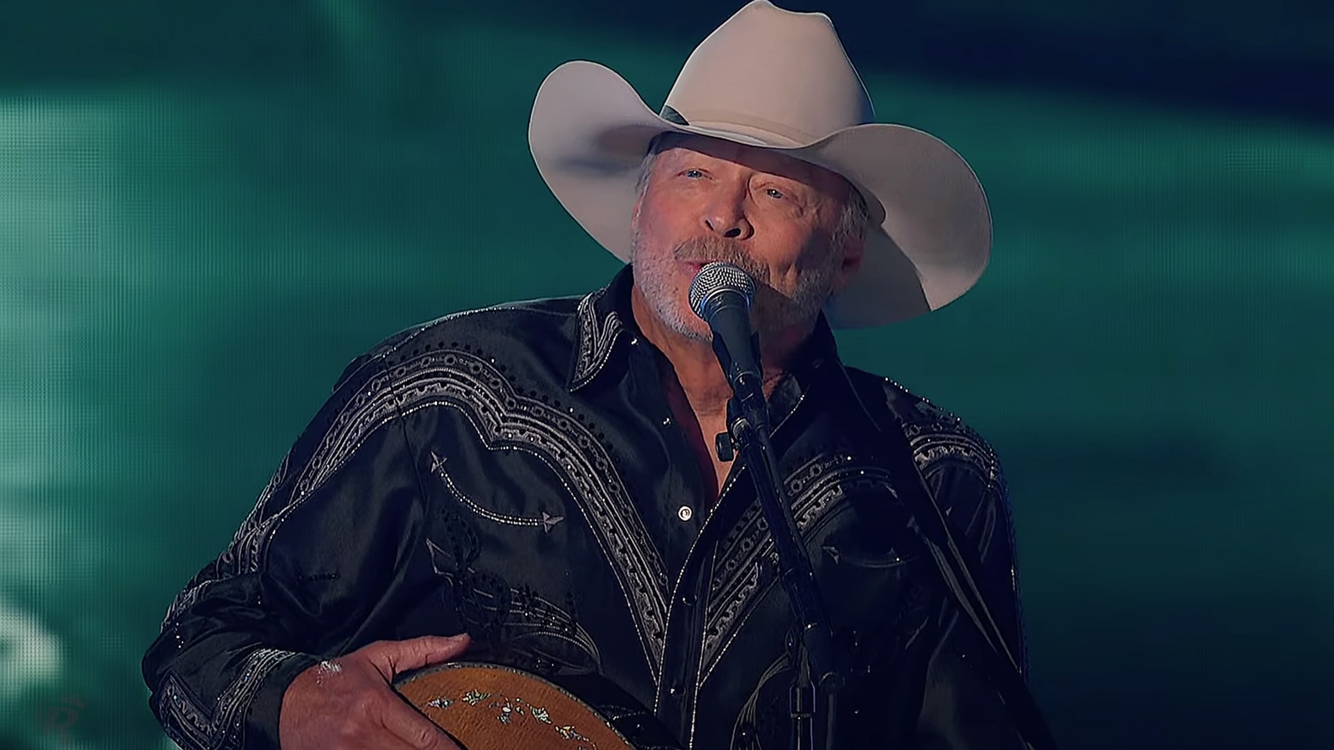 Alan Jackson performs an emotional rendition of "Remember When" at the 2025 ACM Awards, wearing a black embroidered western shirt and white cowboy hat as he strums his guitar and moves the audience to tears.