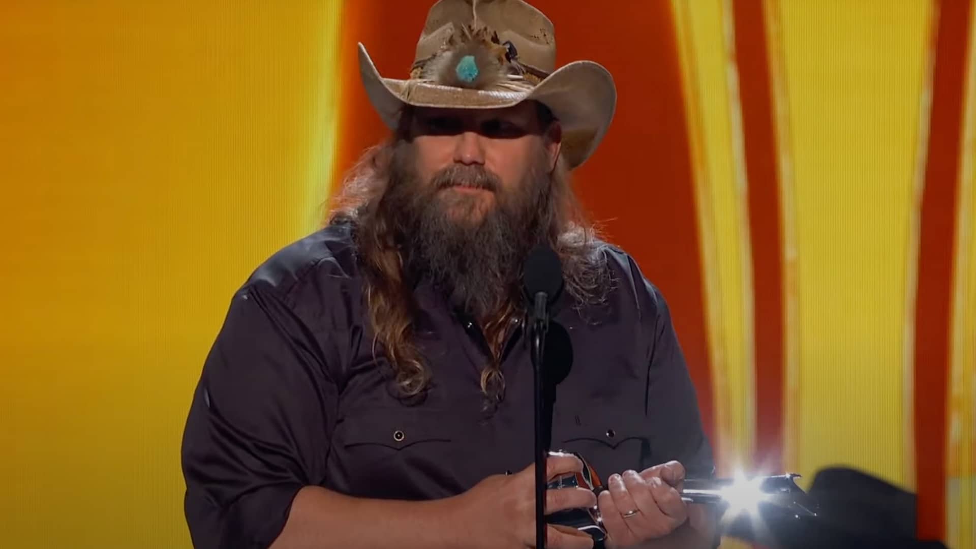 Chris Stapleton accepts the Male Artist of the Year award at the 2025 ACM Awards, holding the trophy and speaking into the mic with emotion during a heartfelt tribute.