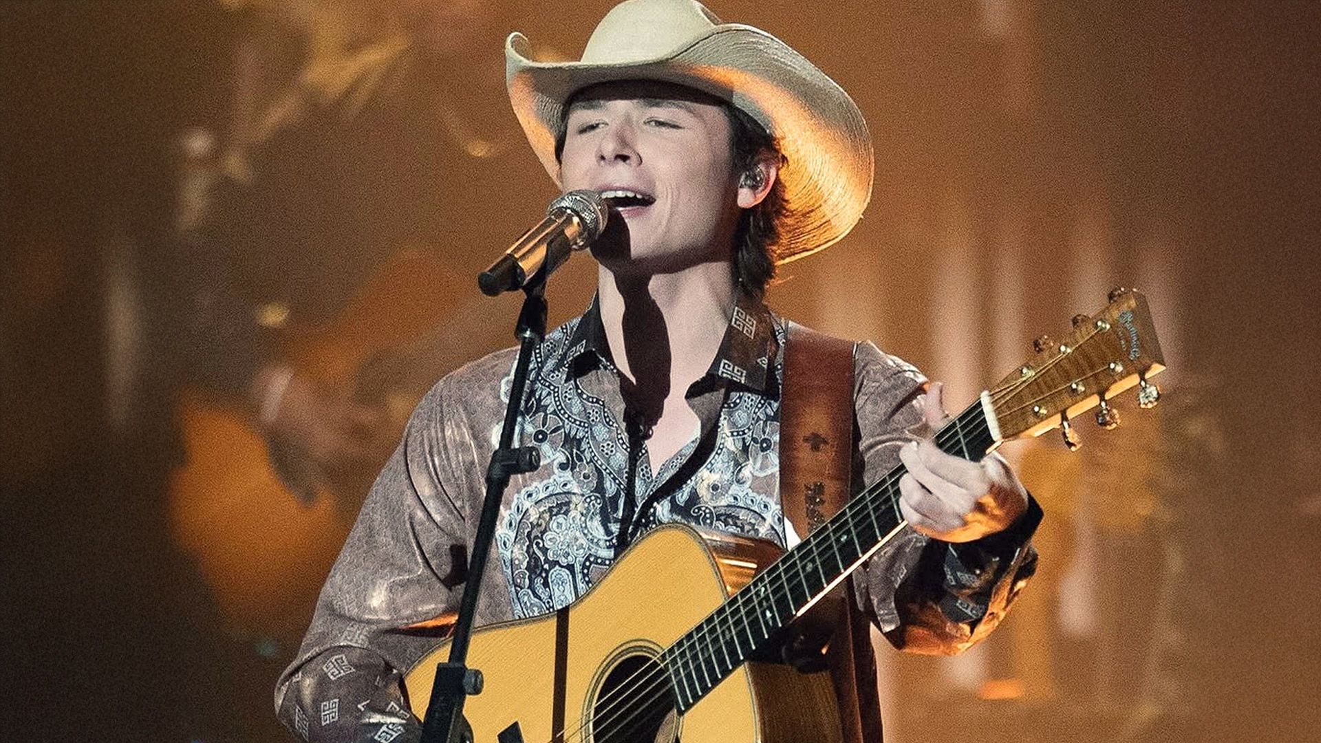 John Foster performs live onstage in a cowboy hat with a guitar, ahead of his Grand Ole Opry debut on June 7.
