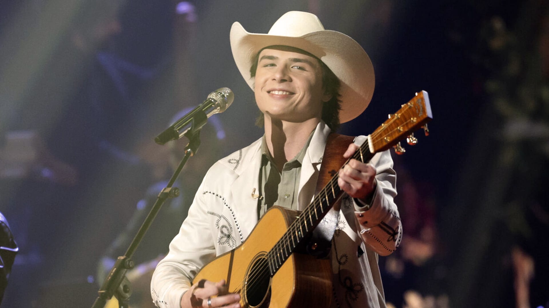 American Idol runner-up John Foster smiles while performing on stage, signaling his bright future in country music despite not taking home the crown.