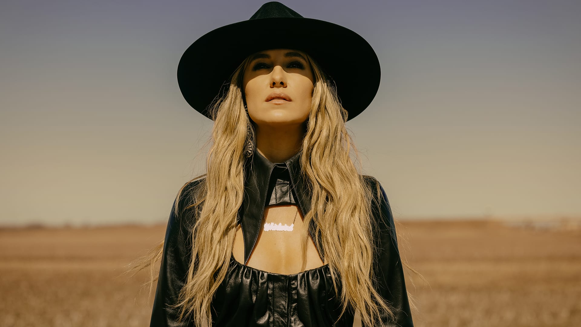 Lainey Wilson poses in a wide-brimmed hat and leather outfit ahead of her feature film debut in Colleen Hoover’s Reminders of Him.