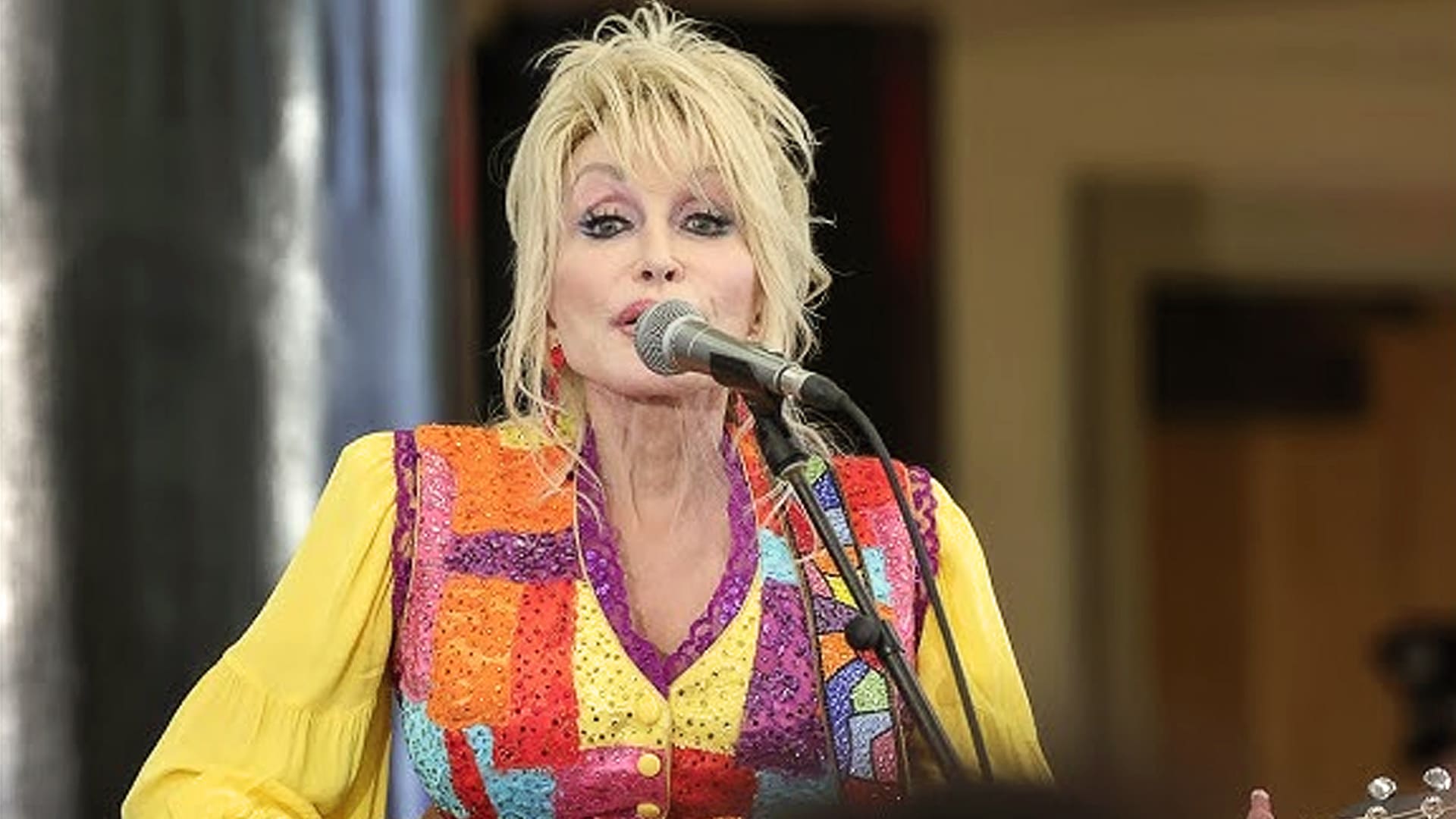 Dolly Parton sings onstage in a vibrant patchwork outfit, following reports that Maren Morris unintentionally echoed her iconic “9 to 5” in a new song.