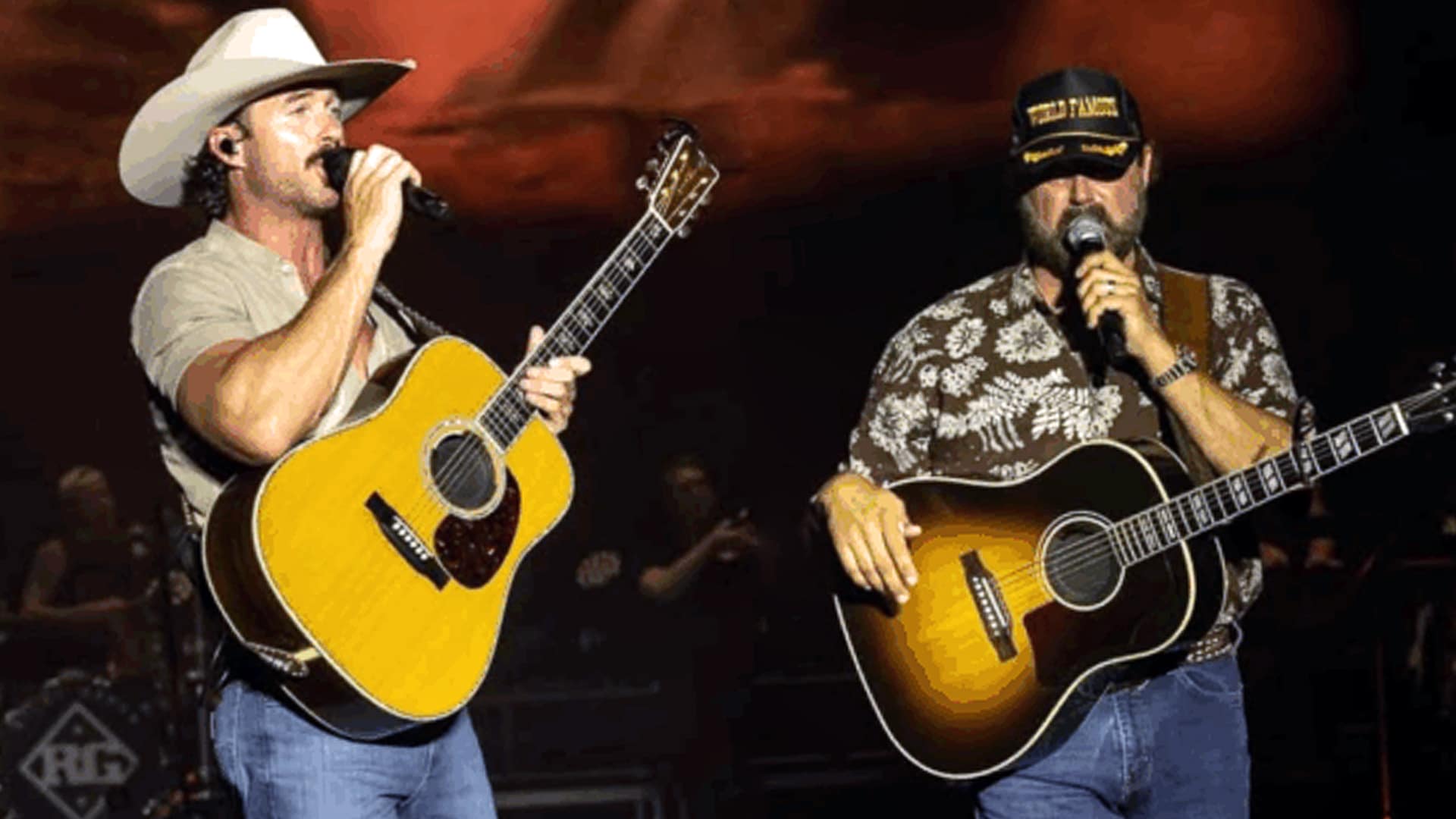 Riley Green and Randy Houser perform with acoustic guitars onstage at Sand In My Boots Fest, honoring Toby Keith with fiery renditions of his classic songs.