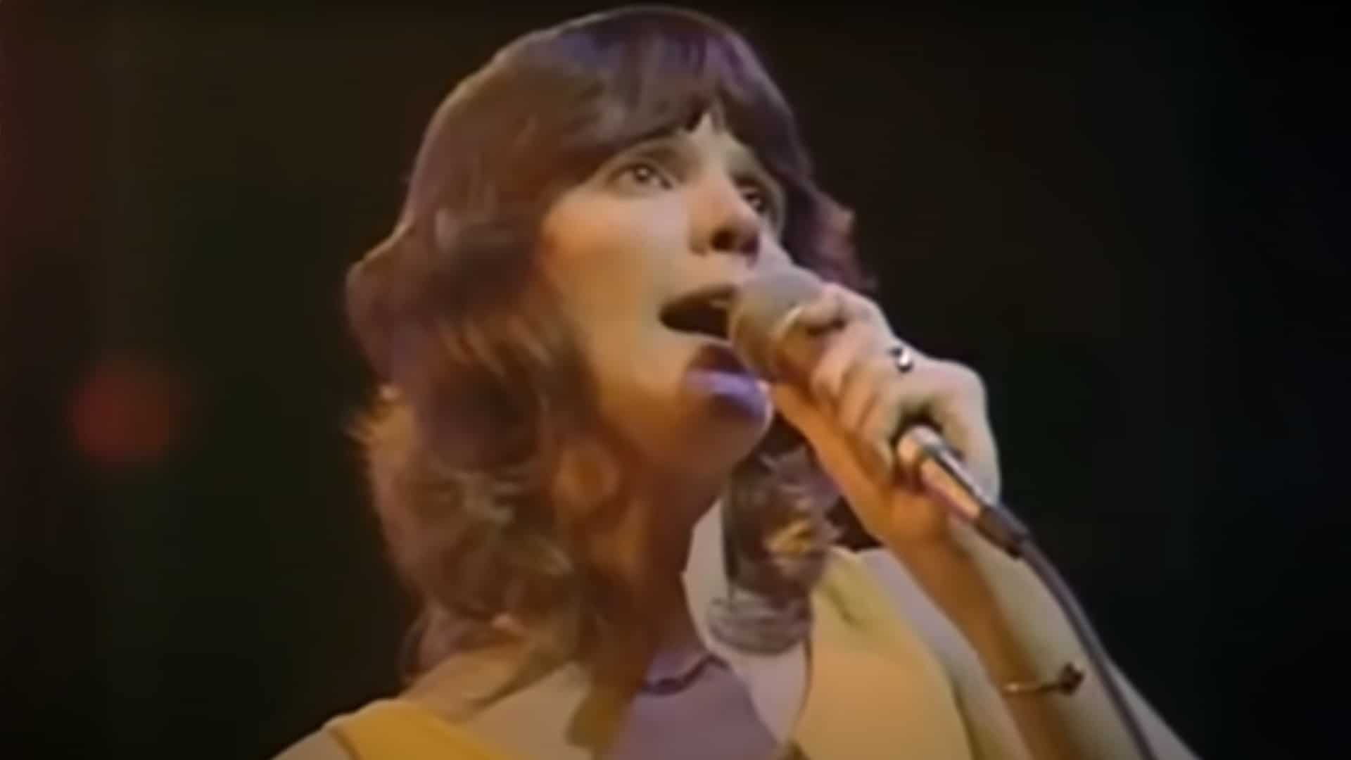 Mary MacGregor performs "Torn Between Two Lovers" live in the 1970s, holding a microphone with a soft, emotional expression that captures the song’s quiet heartbreak.