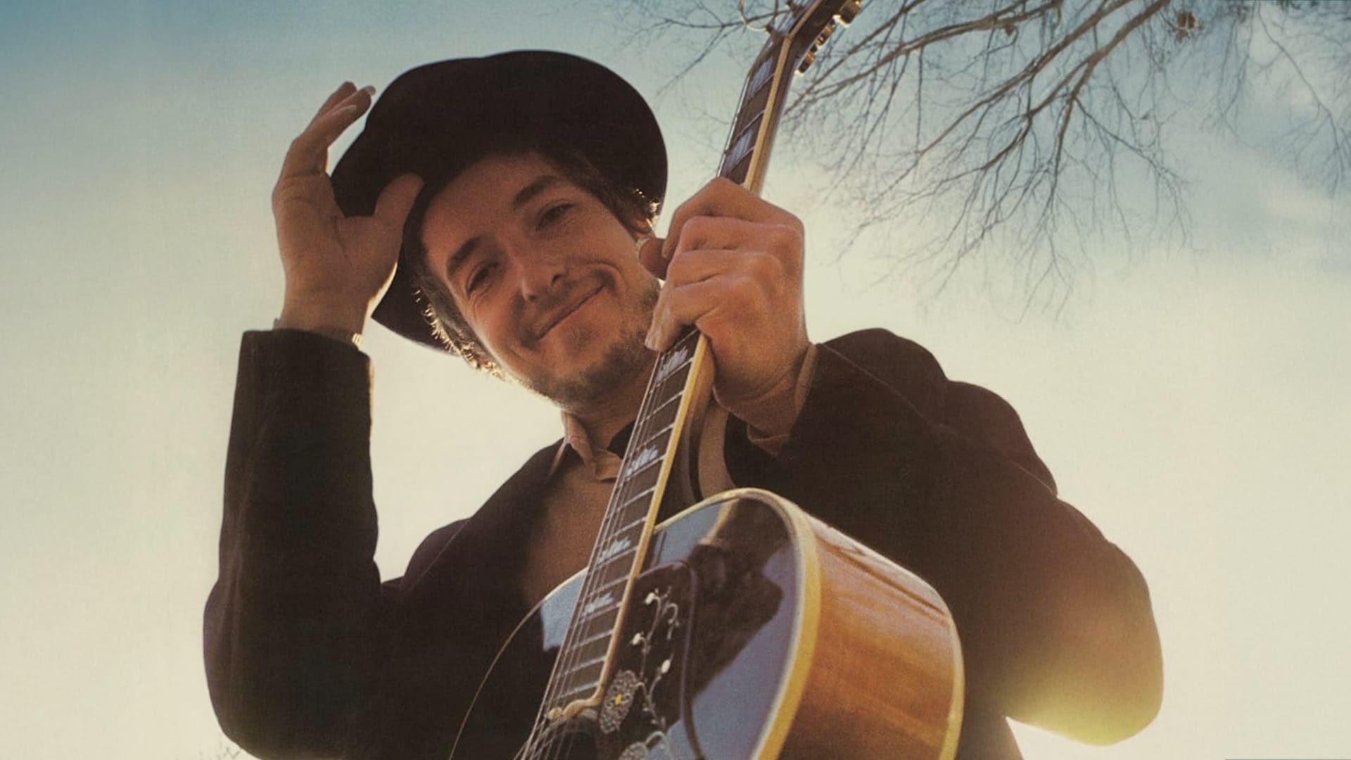 Bob Dylan smiles in a cowboy hat and strums his guitar, marking his bold shift from protest anthems to mellow country roots.