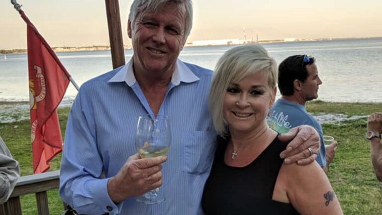 Randy White and Lorrie Morgan smile together at a waterfront gathering, capturing a rare and tender moment from their quiet yet lasting love story.