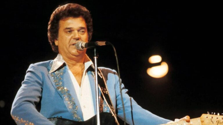 Conway Twitty performs “Hello Darlin’” in a blue embroidered suit, delivering the heartbreak anthem that turned two words into country music history.