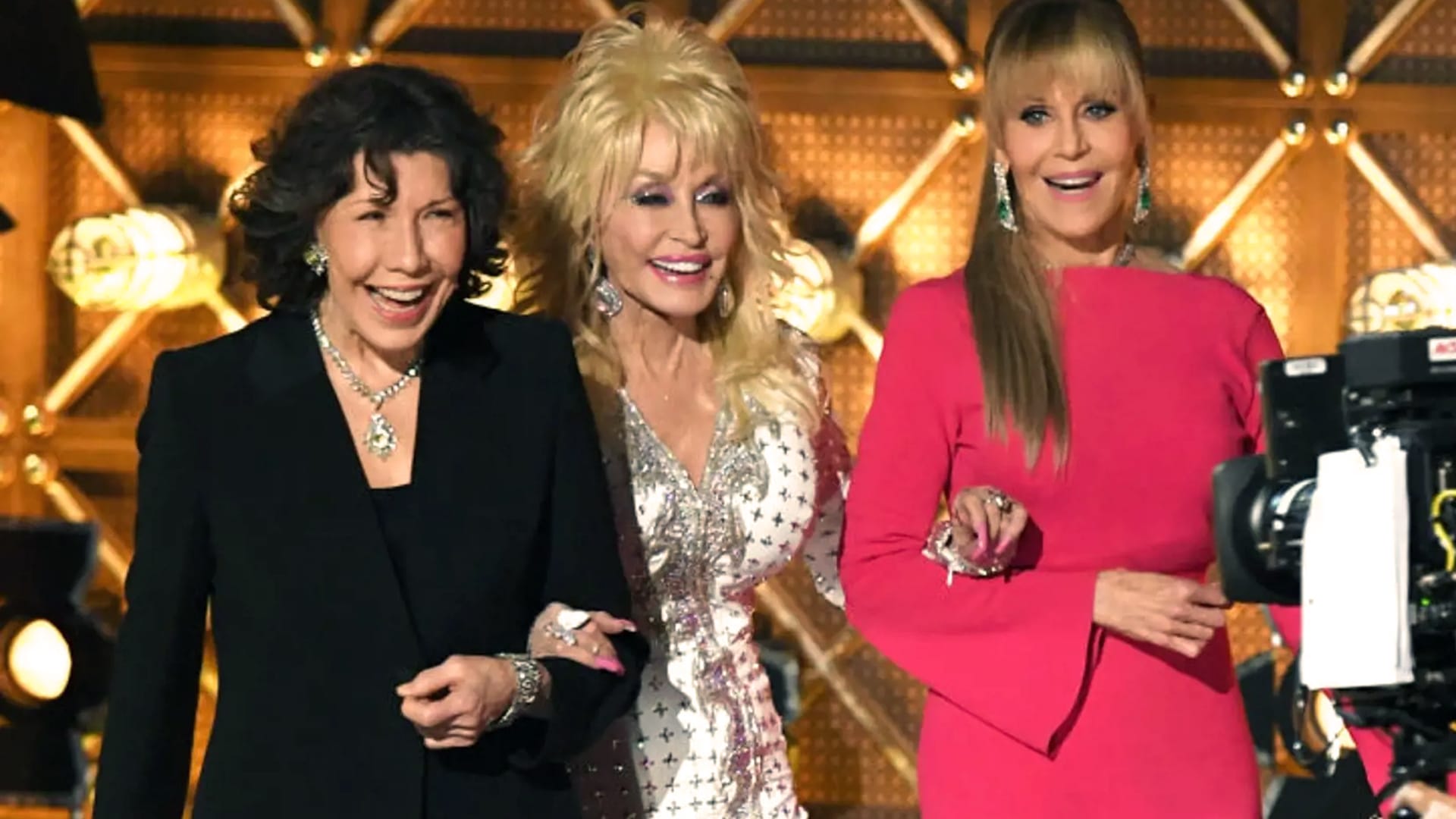 Dolly Parton links arms with Lily Tomlin and Jane Fonda, flashing smiles on set amid talk of the upcoming 9 to 5 remake starring Jennifer Aniston.