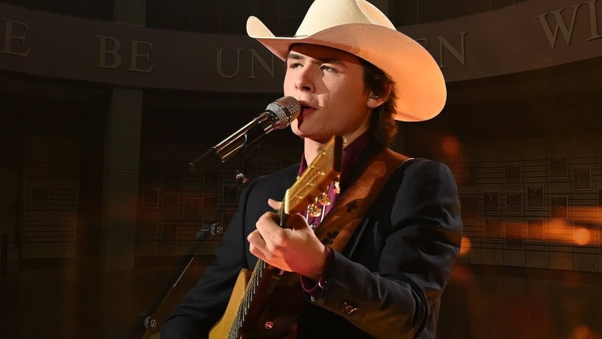 John Foster stands inside the Country Music Hall of Fame, wearing a cowboy hat honoring country music's legacy before his Grand Ole Opry debut.