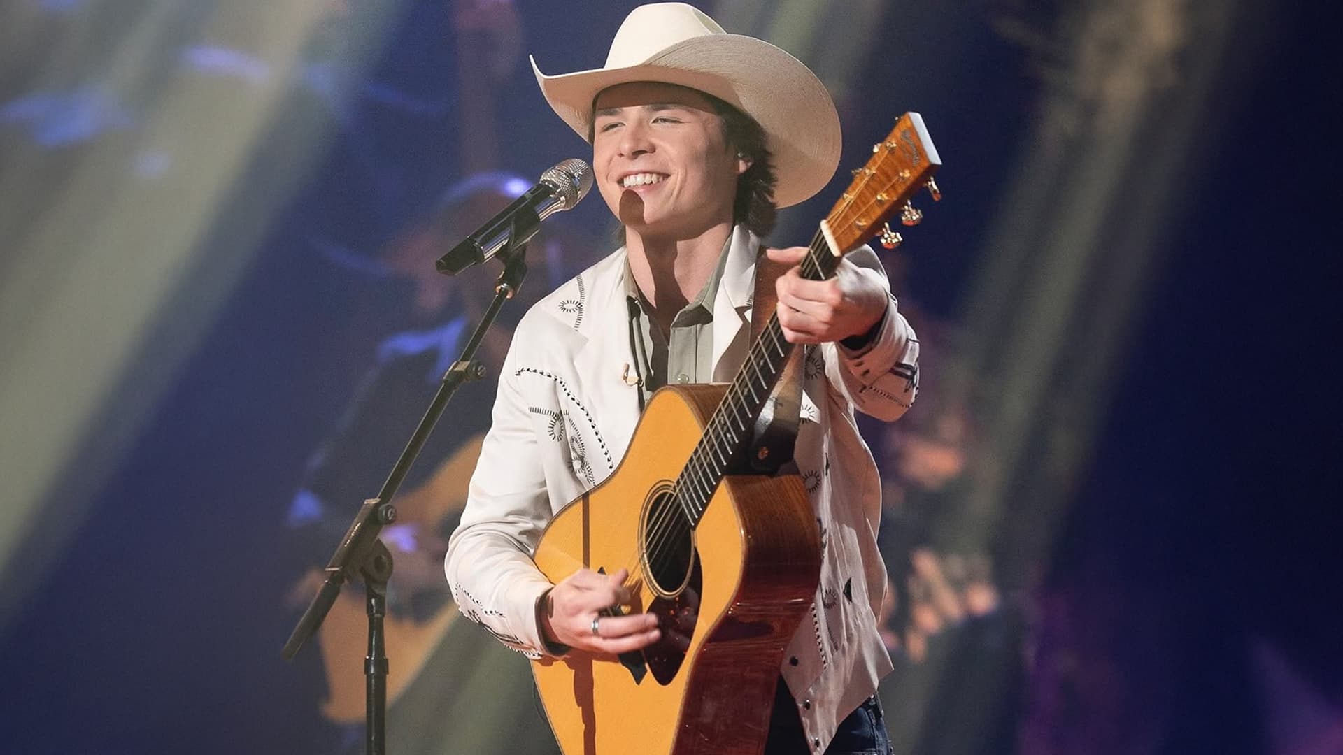 John Foster beams under the spotlight, guitar in hand—looking every bit like the guy who just sold out Baton Rouge in under an hour. Not from that night, but you get the vibe.