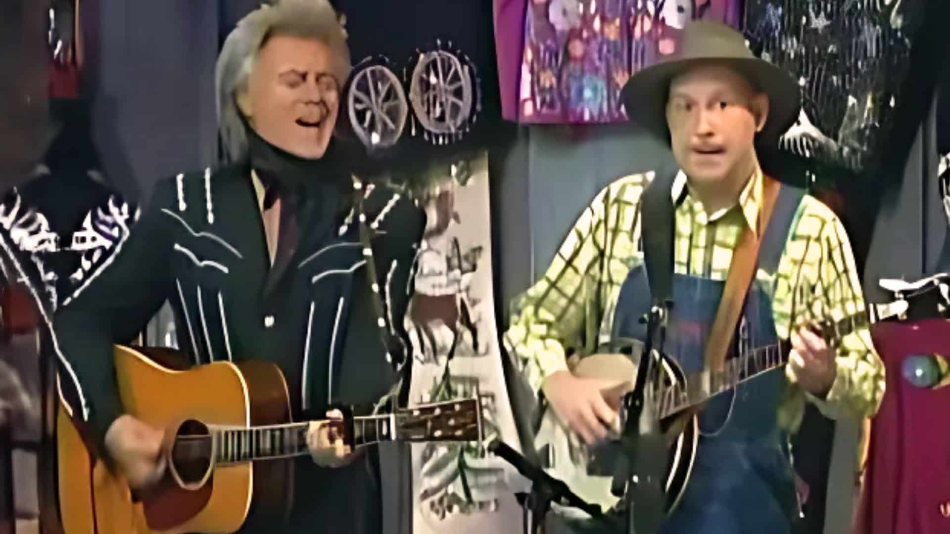 Leroy Troy, dressed in overalls and plaid shirt, performs “Ghost Chickens in the Sky” with Marty Stuart on The Marty Stuart Show, delivering a humorous banjo duet that blends classic country charm with comic brilliance.
