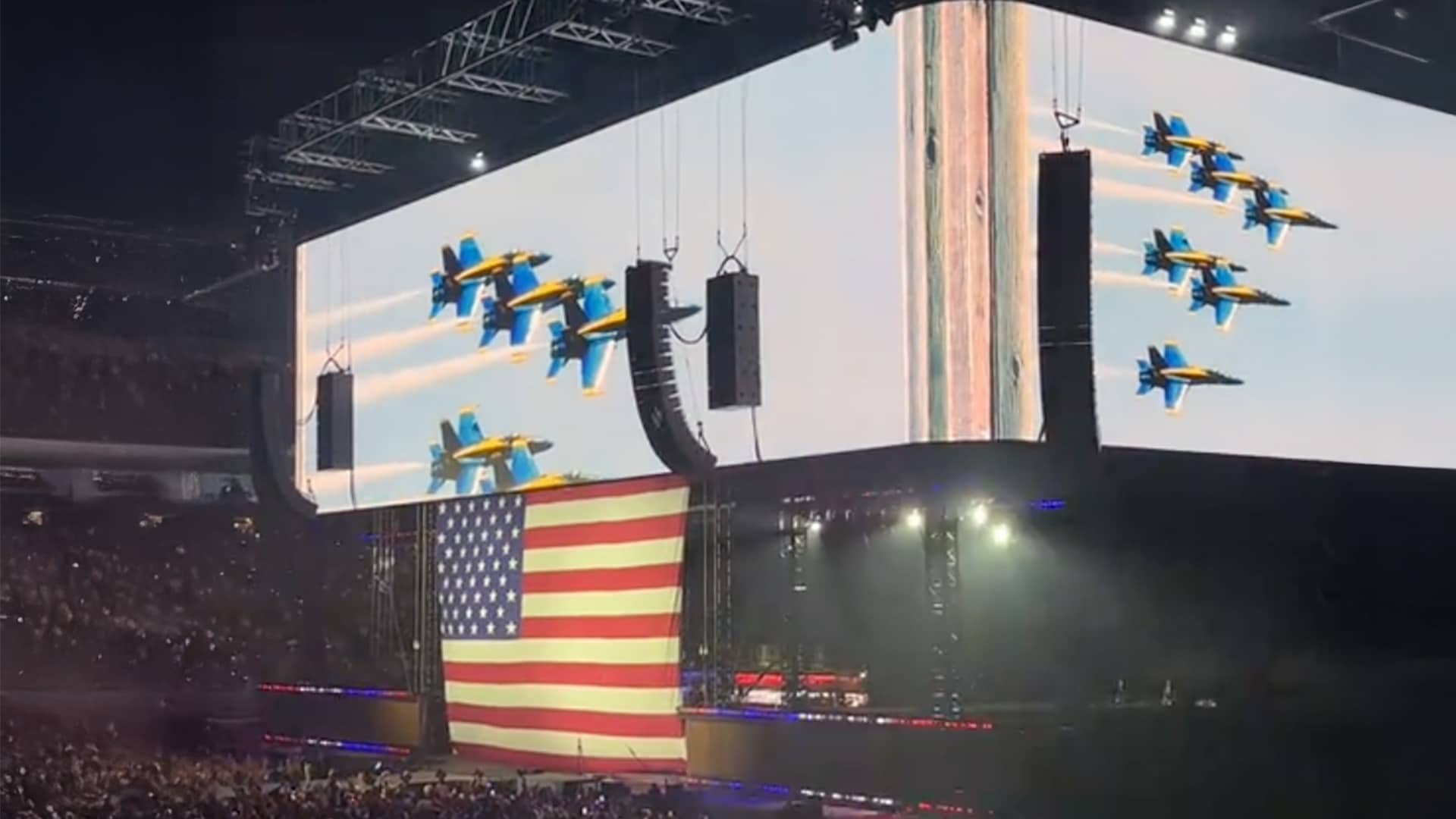 Morgan Wallen performs as a giant American flag drops behind him on stage at NRG Stadium, igniting a patriotic moment.
