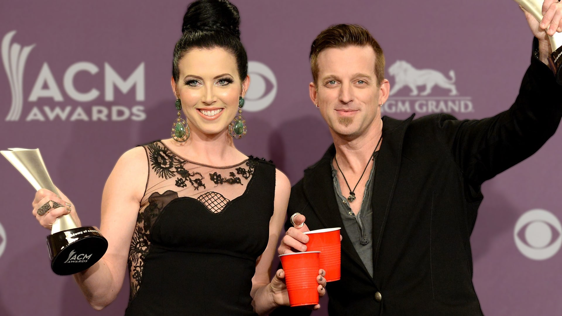 Thompson Square's Keifer and Shawna smile while holding ACM awards and red cups, celebrating with old-school country charm and a firm stance against pop crossover trends.