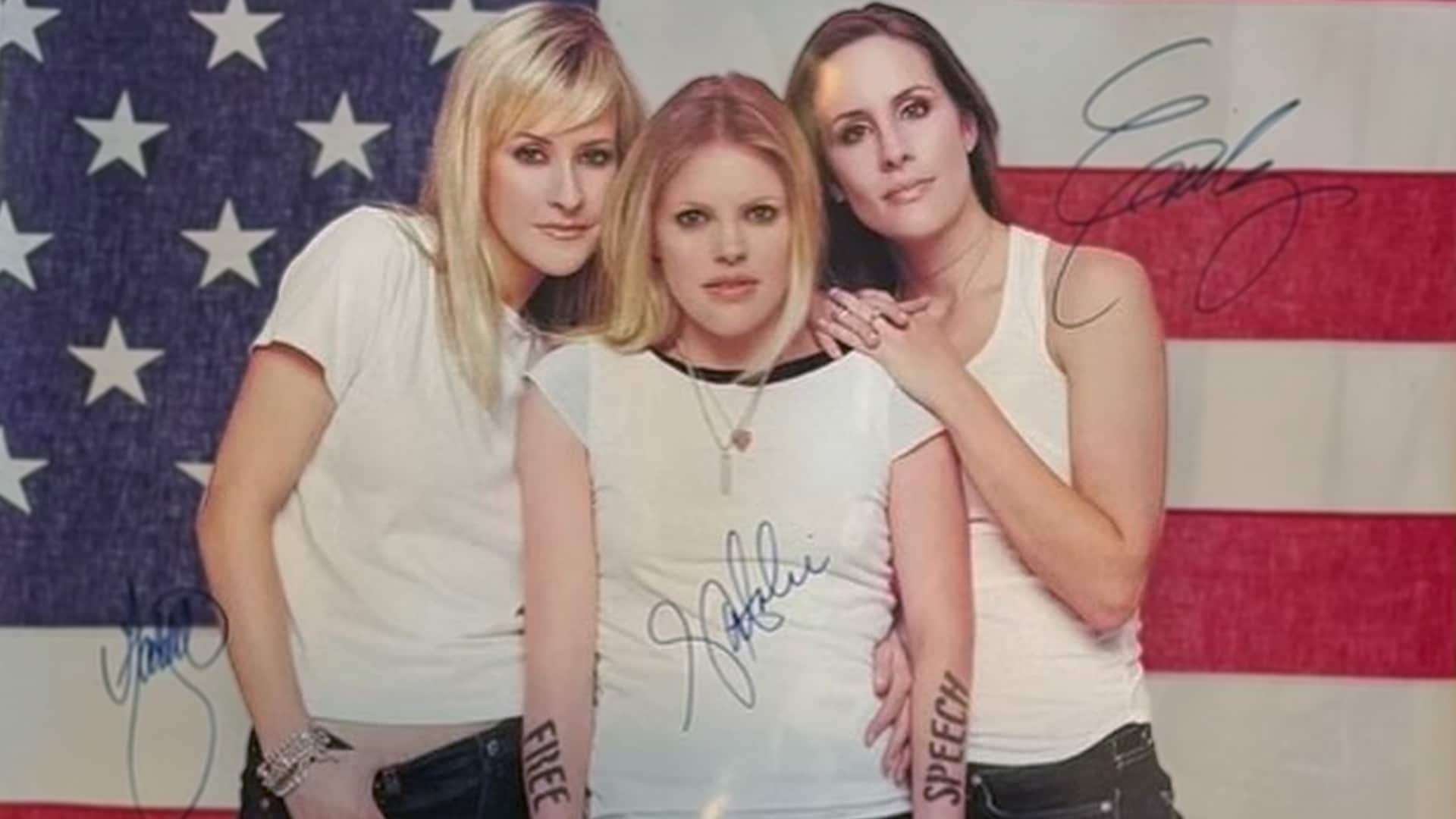 The Dixie Chicks pose in front of an American flag in white T-shirts, with the words "FREE SPEECH" written on their arms—capturing the controversial moment that reshaped their career after 2003.