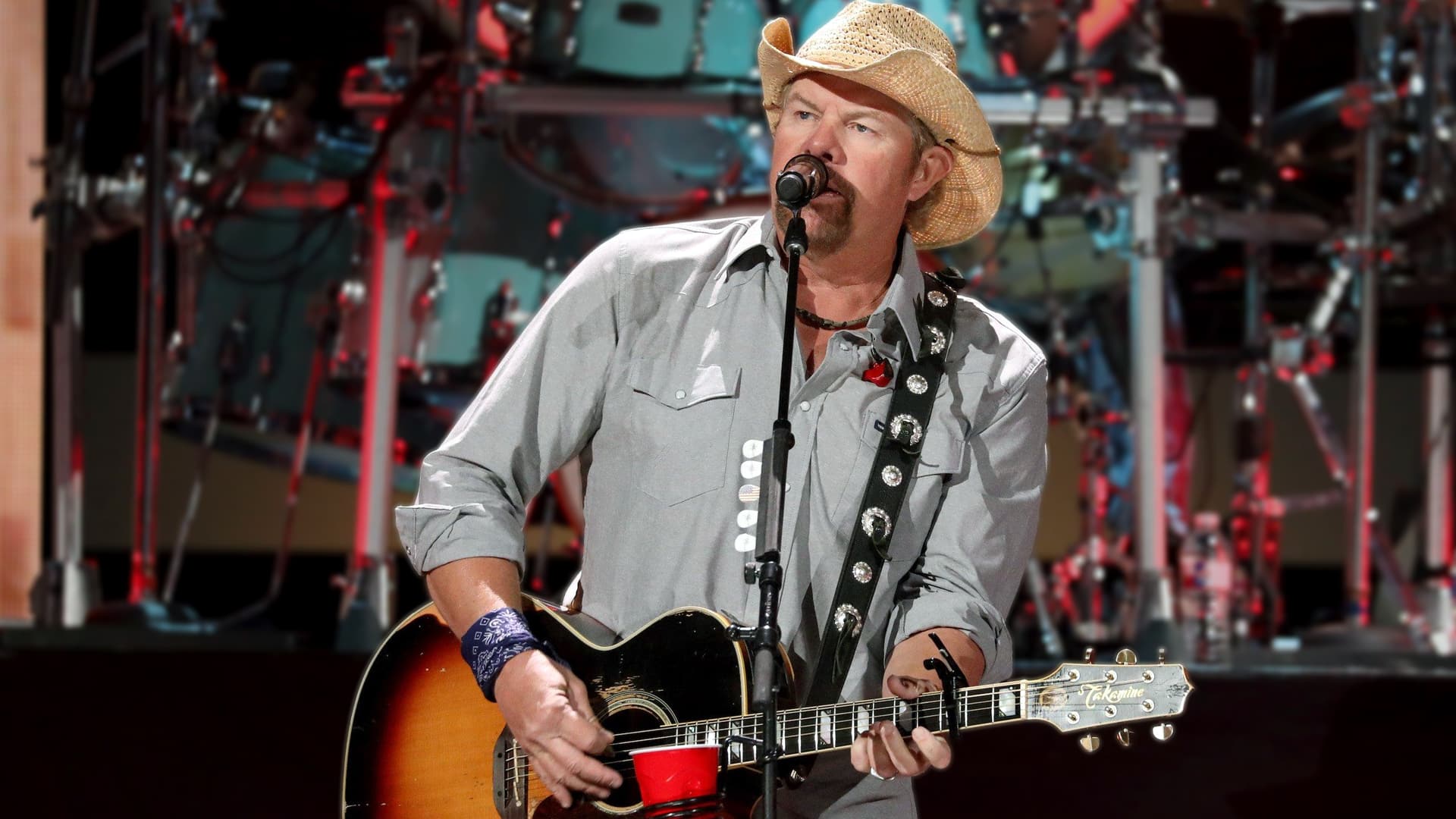 Toby Keith performs live in a cowboy hat while playing guitar, representing one of the 13 controversial country songs that sparked debate but resonated with millions.