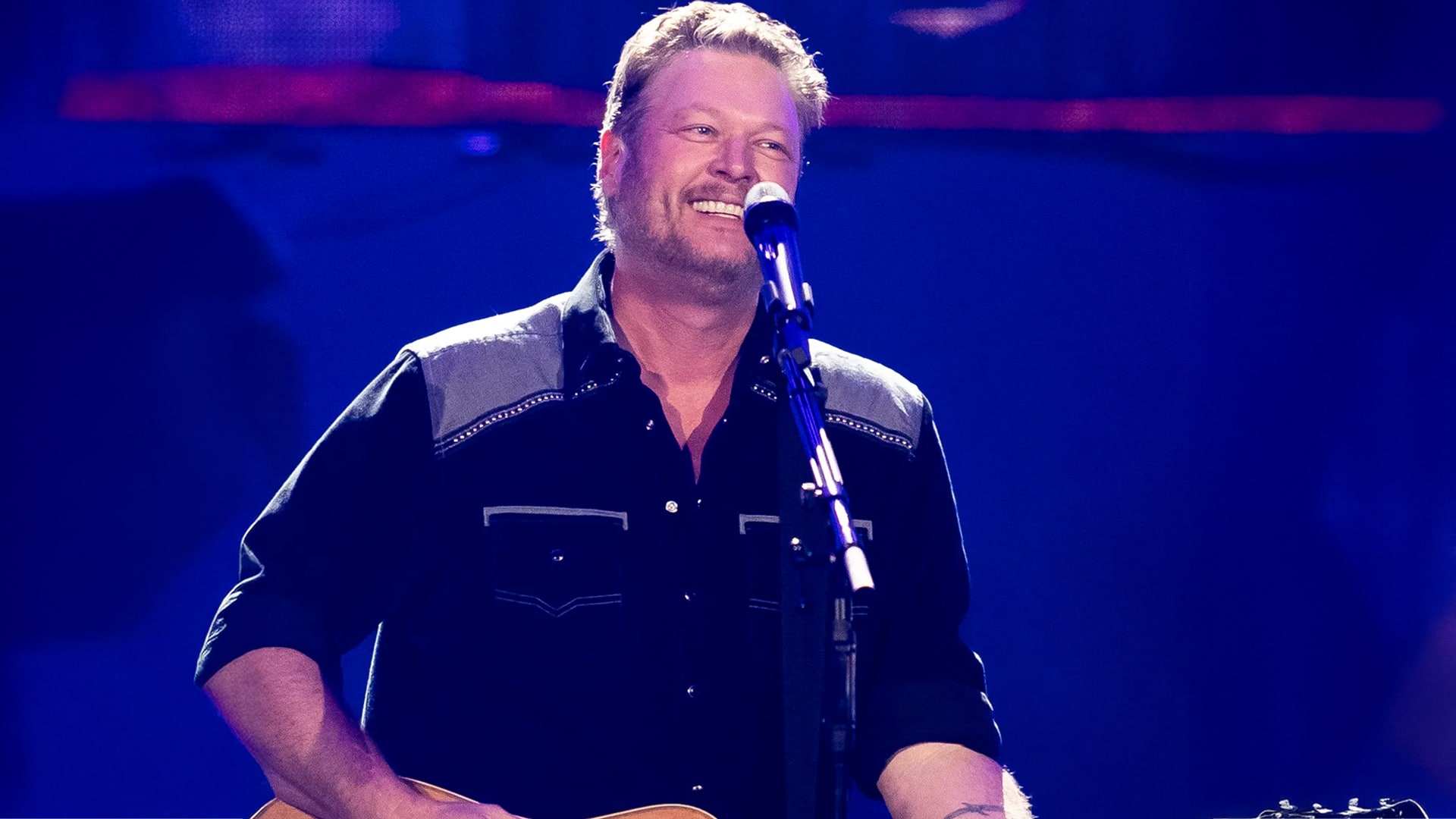 Blake Shelton smiles on stage with guitar and mic during Vegas show, putting his own spin on George Strait’s classic.