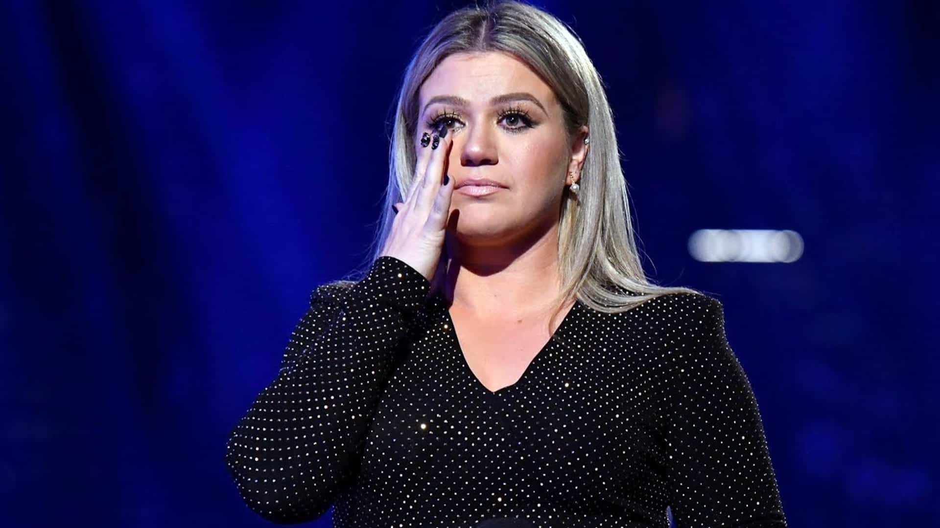 Kelly Clarkson seen emotional in a past photo, echoing fans’ heartbreak after she canceled her Vegas opening night due to illness.
