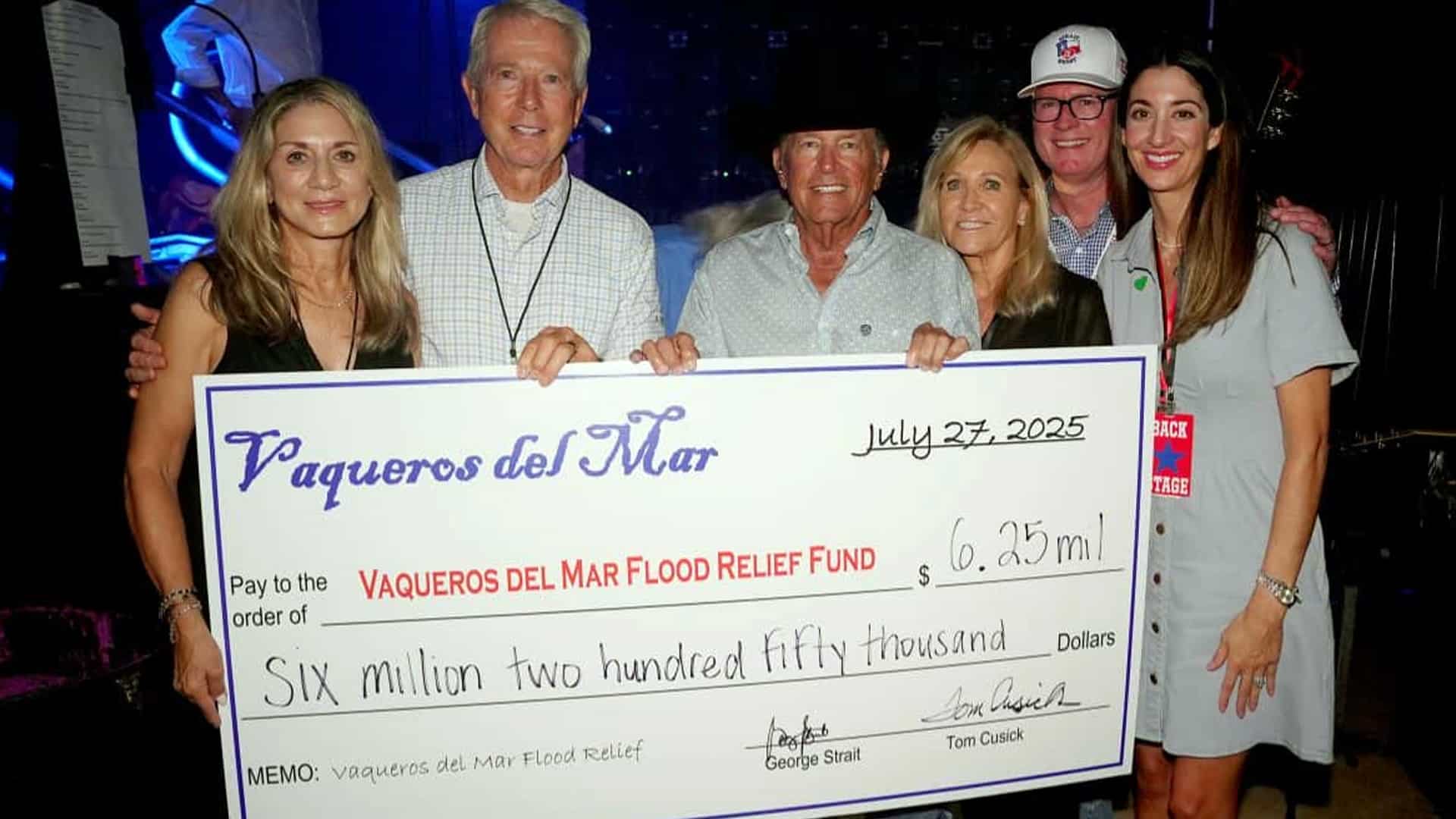 George Strait stands with supporters holding a giant $6.25 million donation check for Texas flood relief at the Vaqueros del Mar benefit event.
