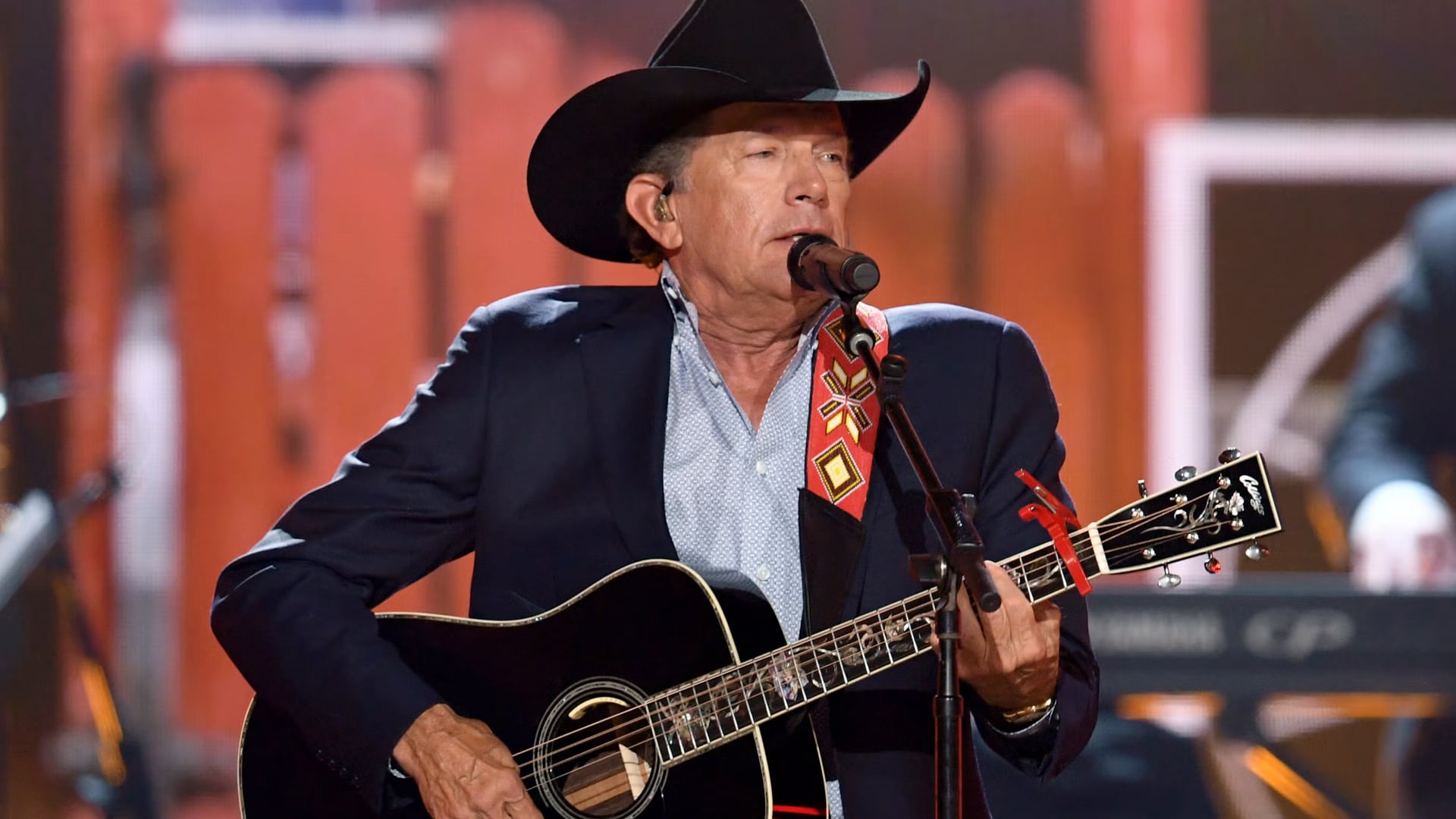 George Strait performing on stage with his guitar and cowboy hat, pictured at a previous event not related to the upcoming Strait From the Heart benefit concert.