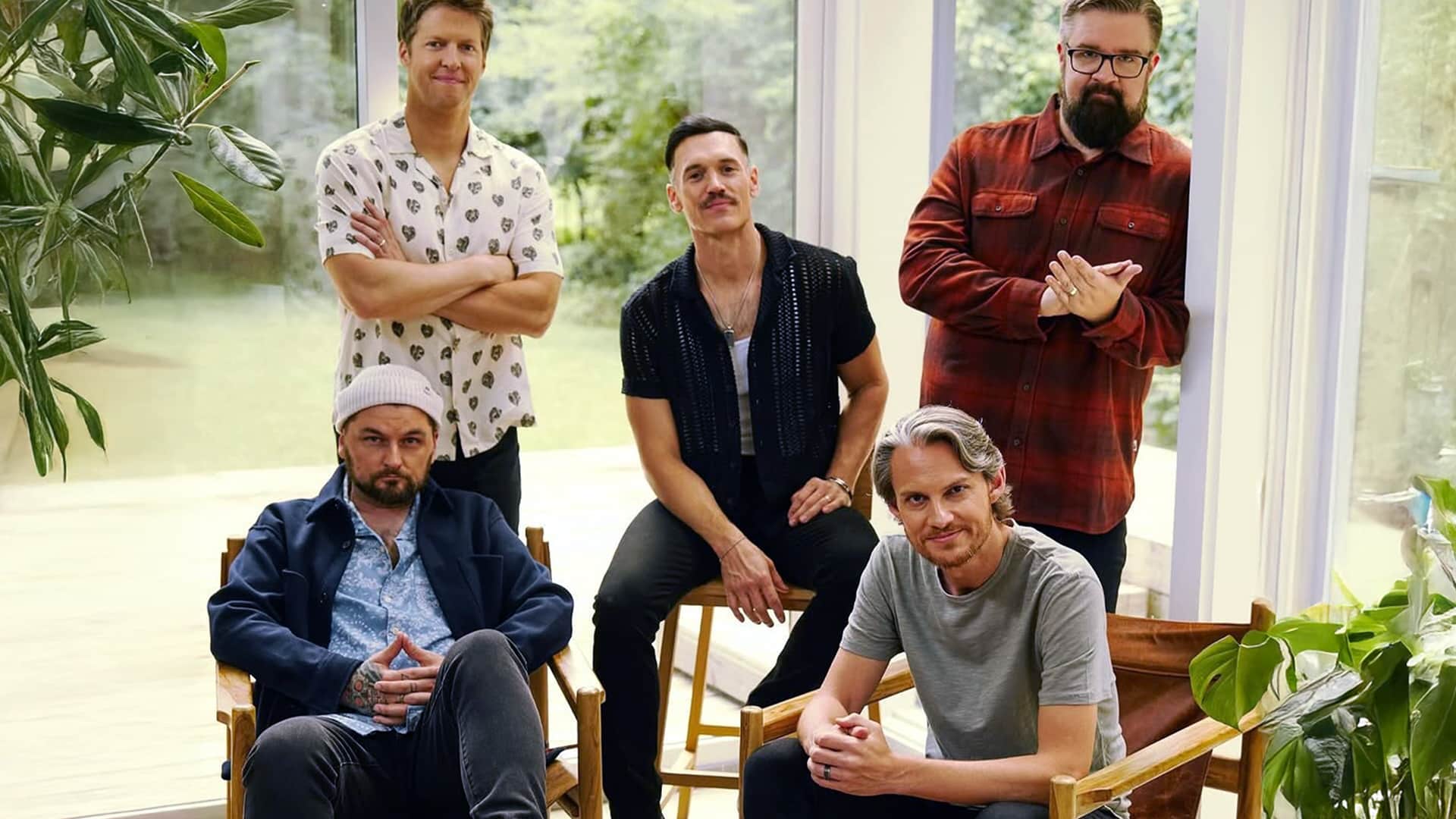 The five current members of country a cappella group Home Free pose together indoors, showcasing their unique styles and tight bond as vocal performers.