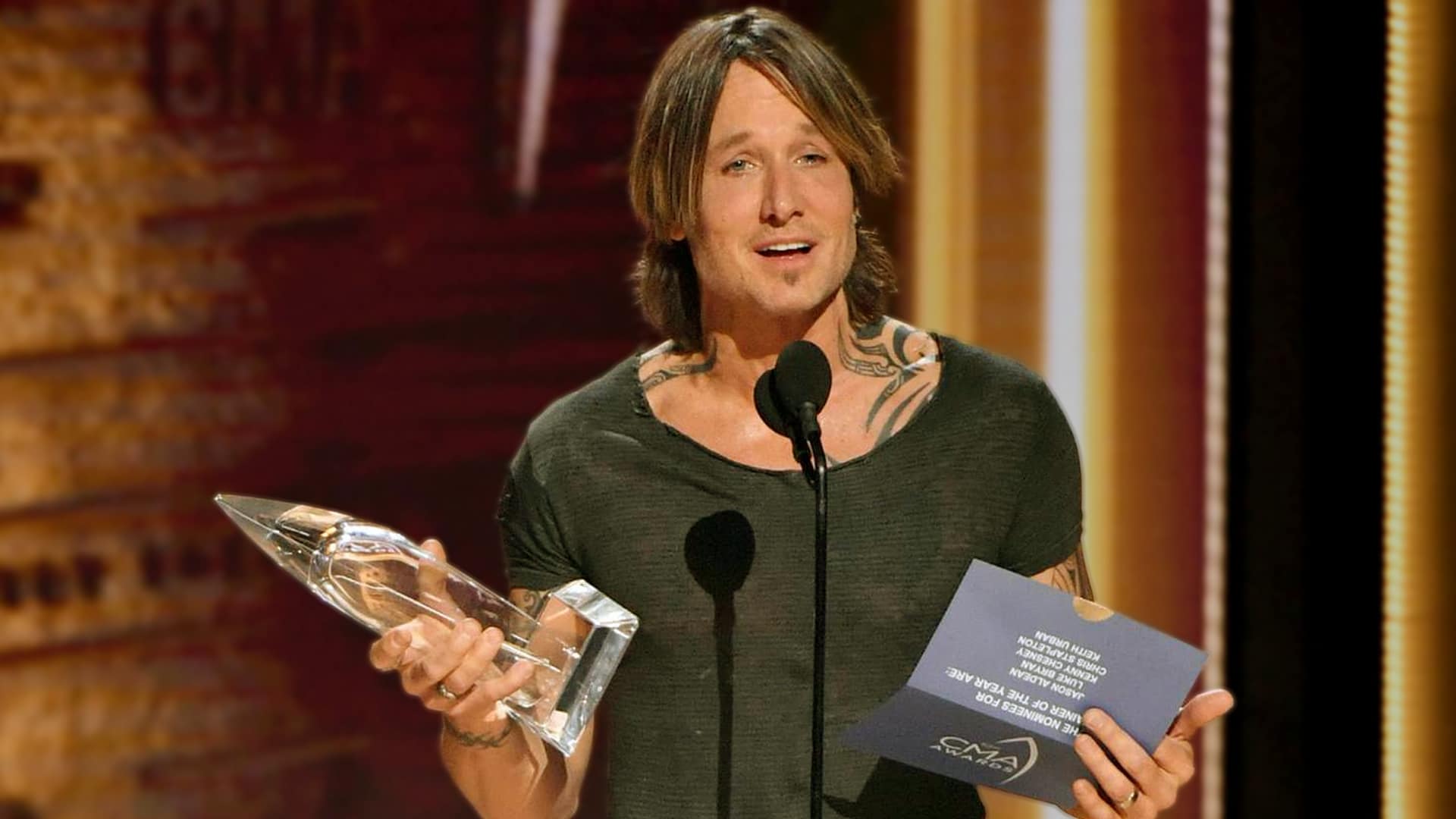Keith Urban holds a CMA award on stage, showing the same trophies he often ships home so his mom can keep a room full of them.
