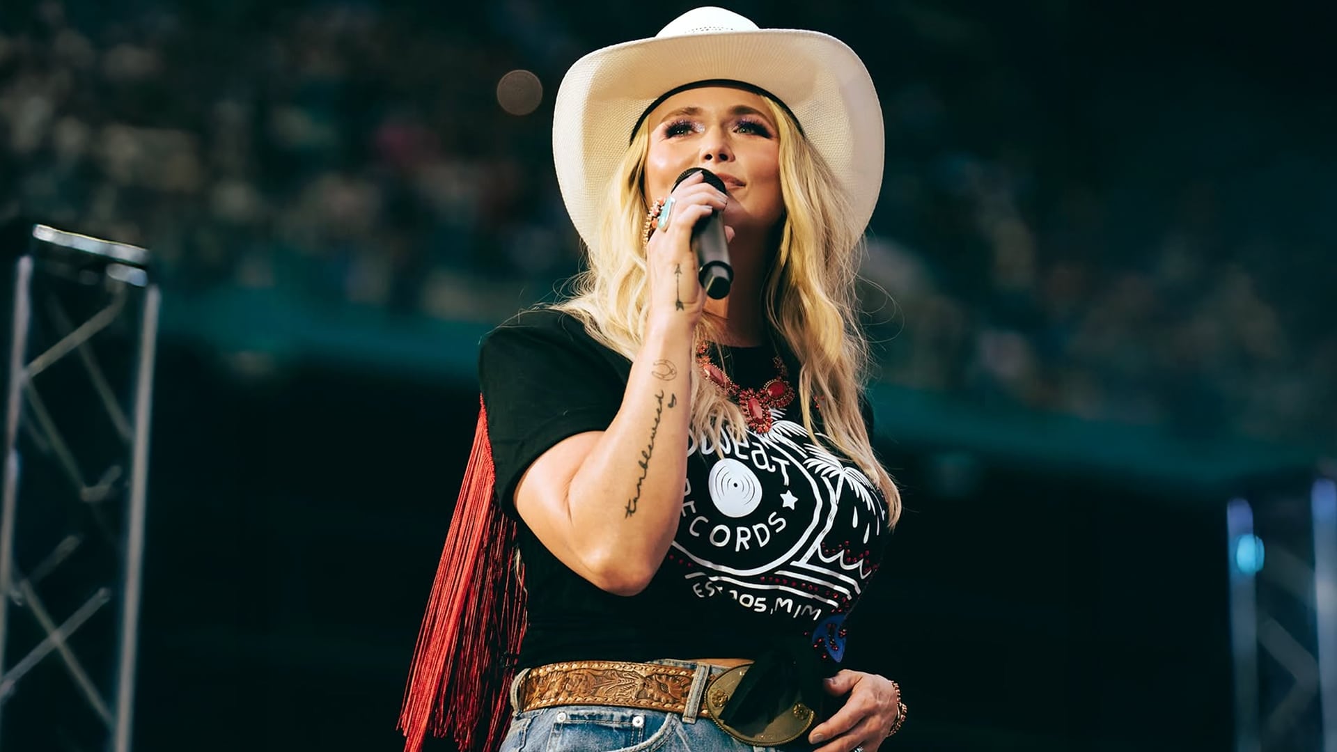 Miranda Lambert stands onstage in a white cowboy hat and fringe top, radiating confidence after shaking off her preshow jitters at Morgan Wallen’s Miami tour stop.