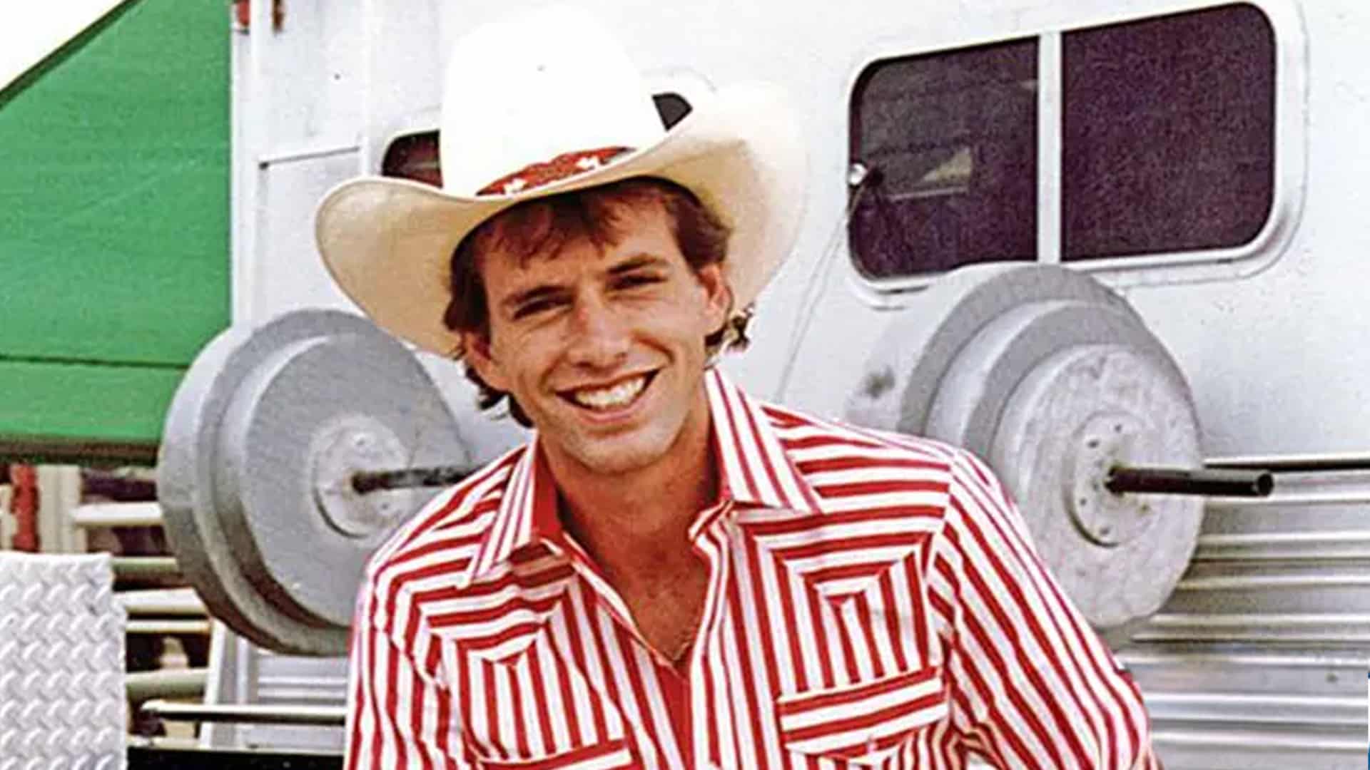 Lane Frost smiles in a red and white striped shirt and cowboy hat, remembered 36 years after his tragic final bull ride at Cheyenne Frontier Days.