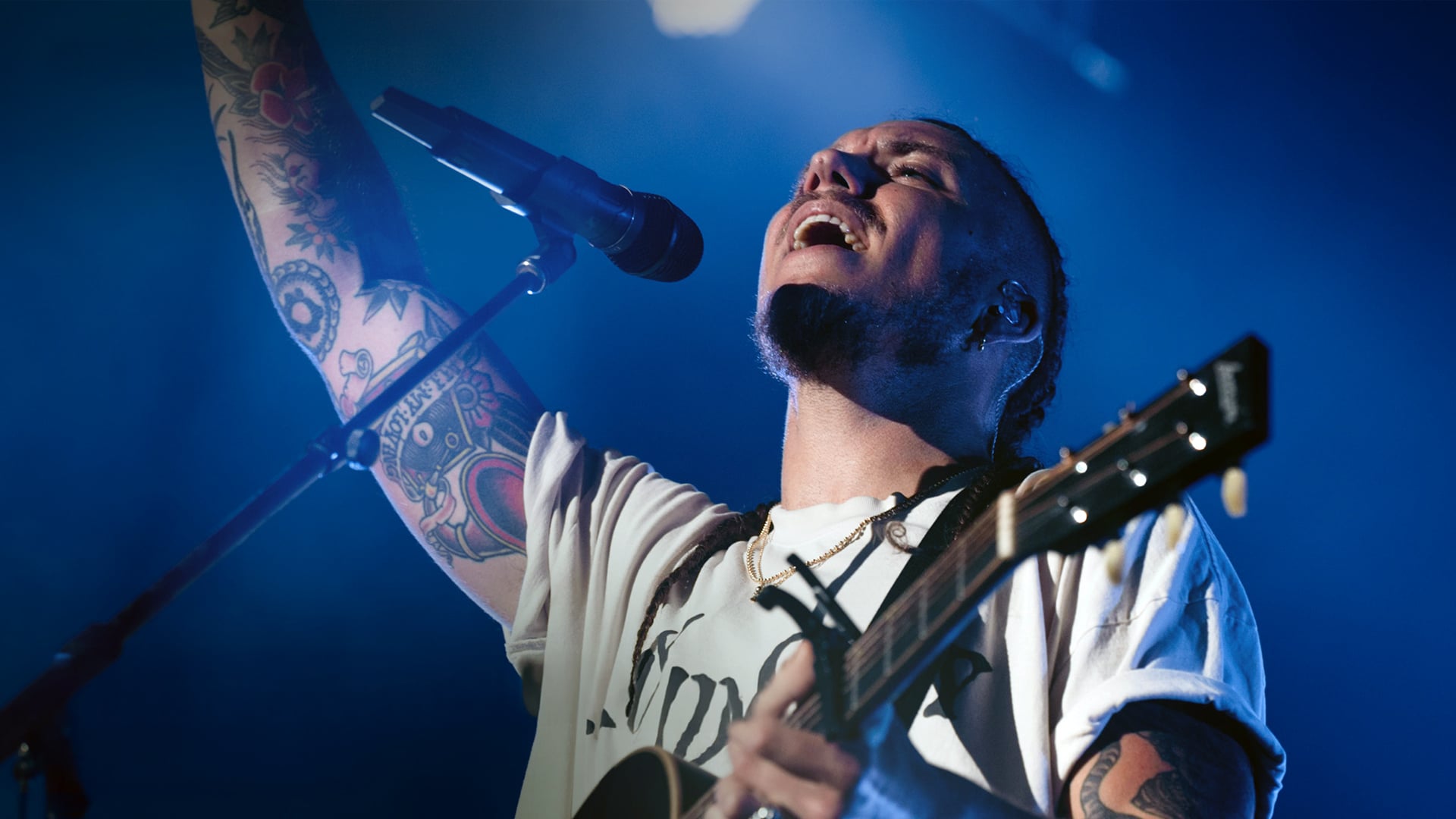 Christian artist performs passionately onstage with raised arm and guitar, capturing the bold energy behind faith-driven songs now shaking up the Billboard Hot 100.