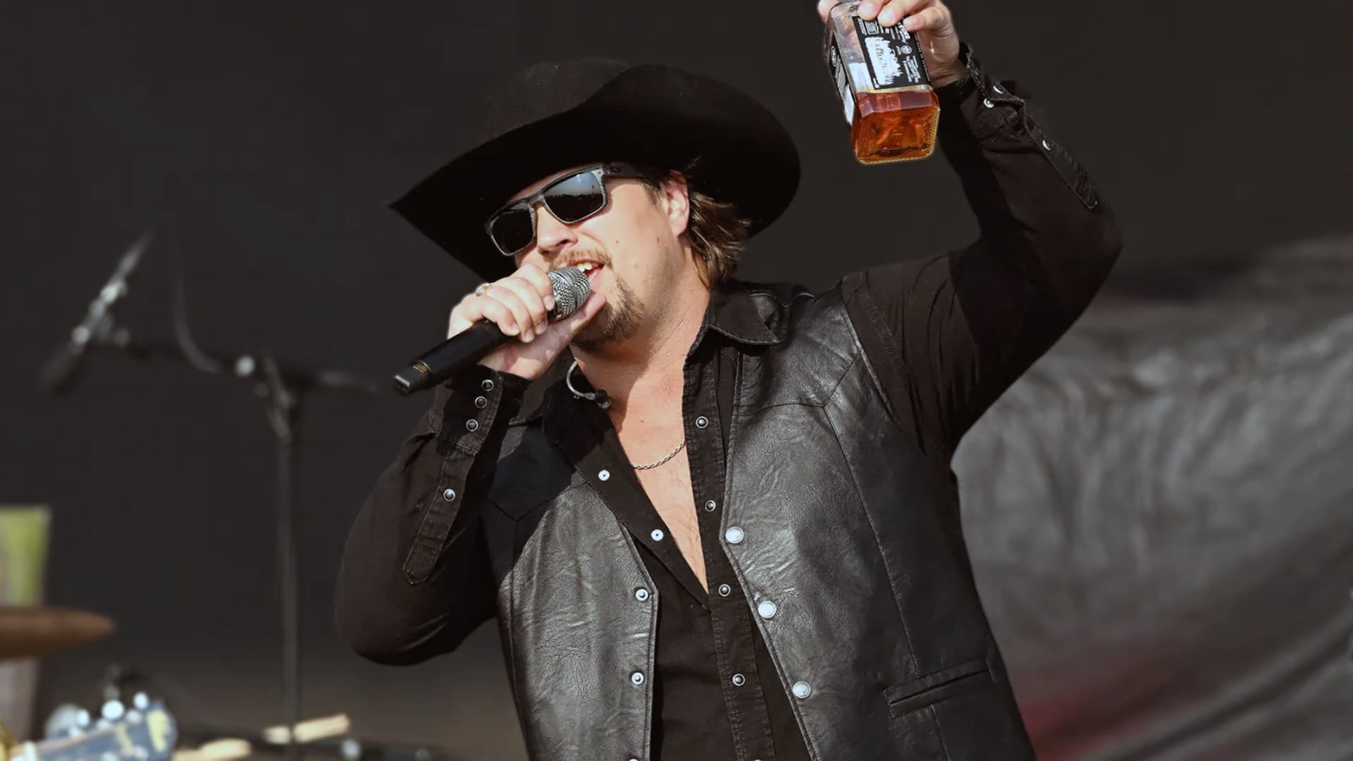 Gavin Adcock onstage raising a whiskey bottle while blasting Beyoncé’s ‘Cowboy Carter’ as “not real country music.”