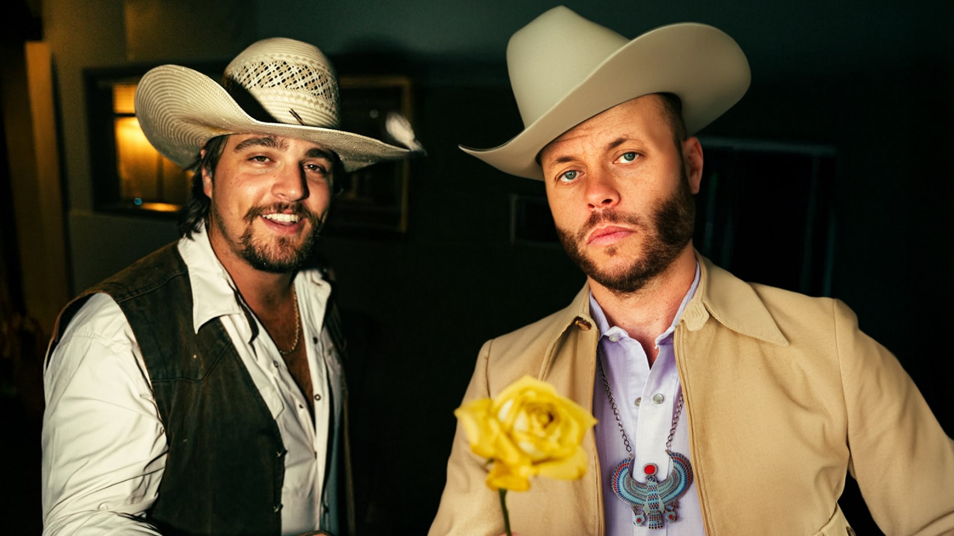 Gavin Adcock and Charley Crockett in cowboy hats, with Crockett offering a rose as their dispute takes a surprising twist.