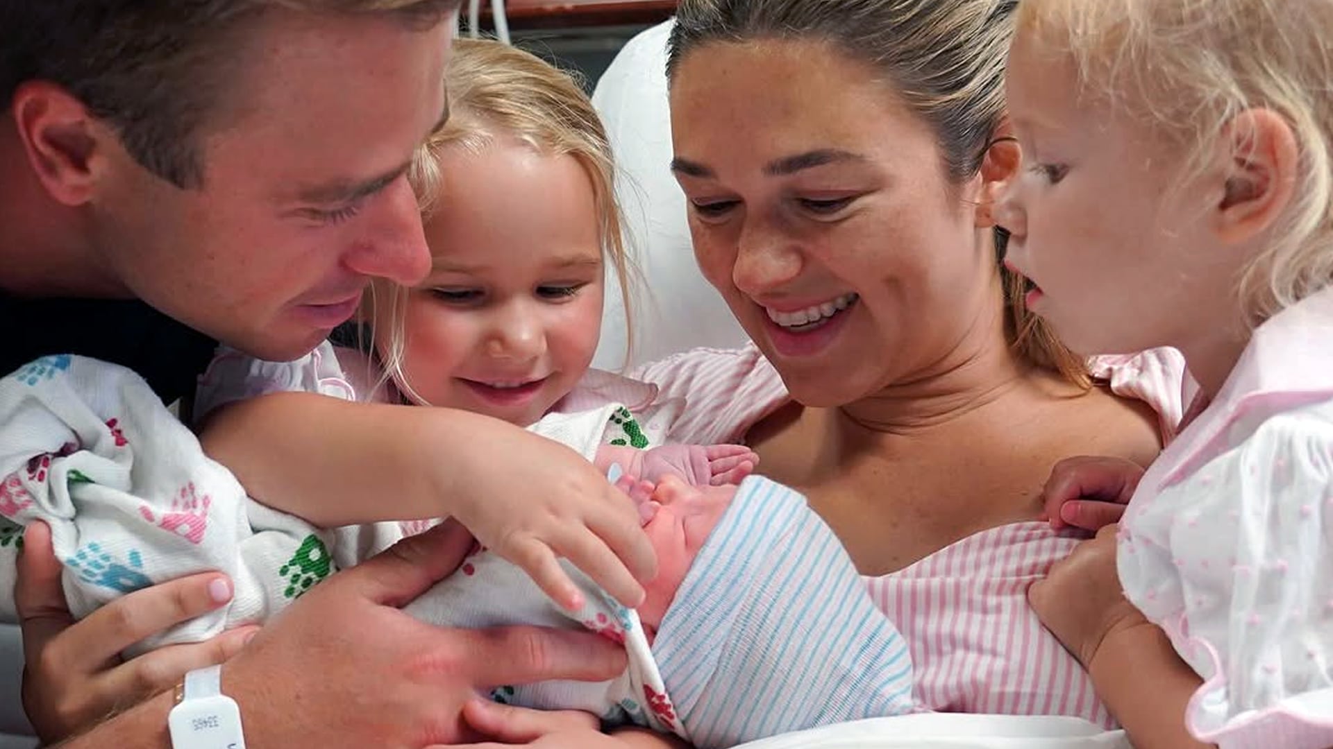 Sadie Robertson Huff and Christian Huff smile joyfully with their two daughters as they introduce their newborn baby girl in a hospital bed.