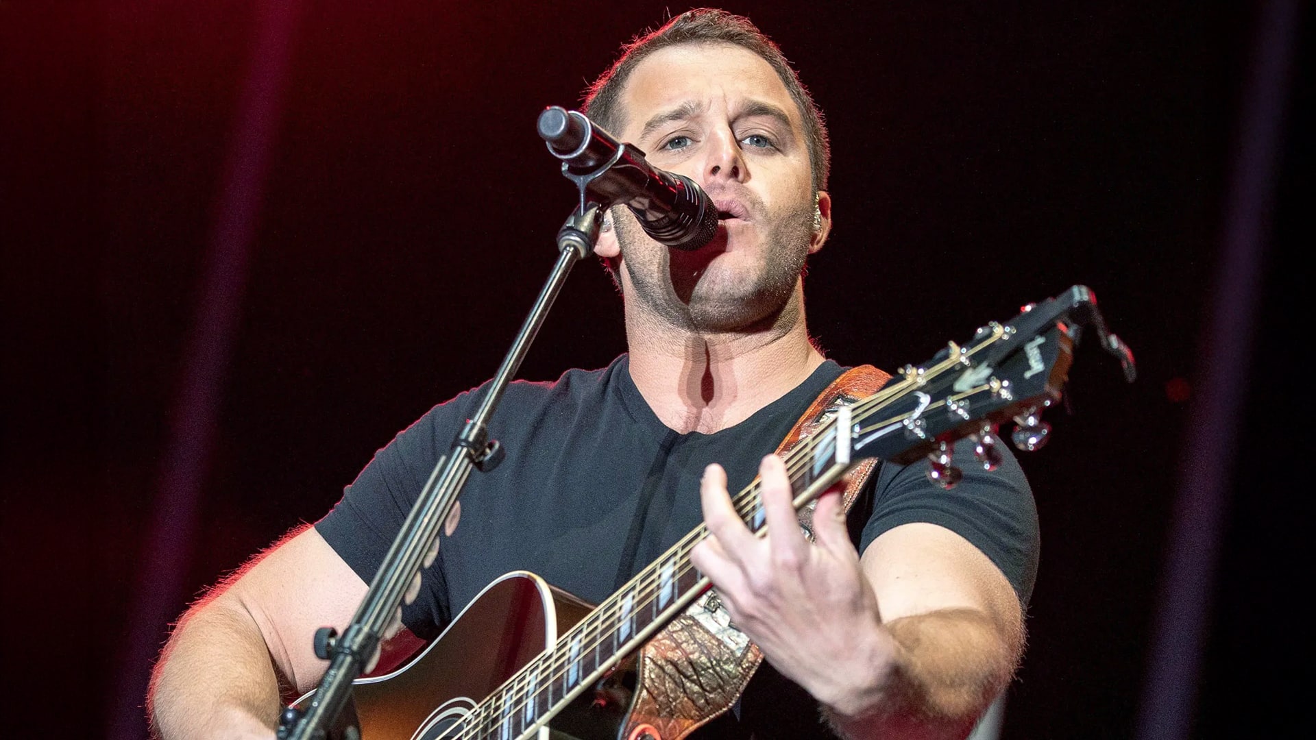 Easton Corbin sings passionately with guitar in hand, pausing his tour to grieve the loss of his stepfather.