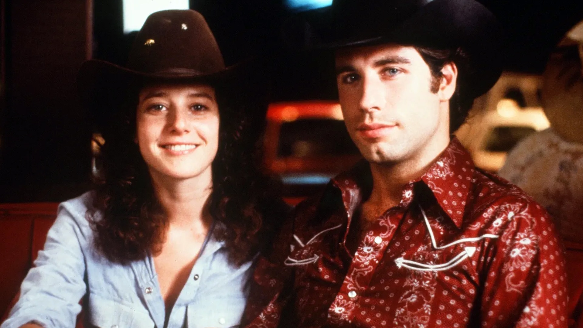 John Travolta and Debra Winger wear cowboy hats and smile in a scene from the 1980 movie Urban Cowboy, which sparked a national honky-tonk craze.