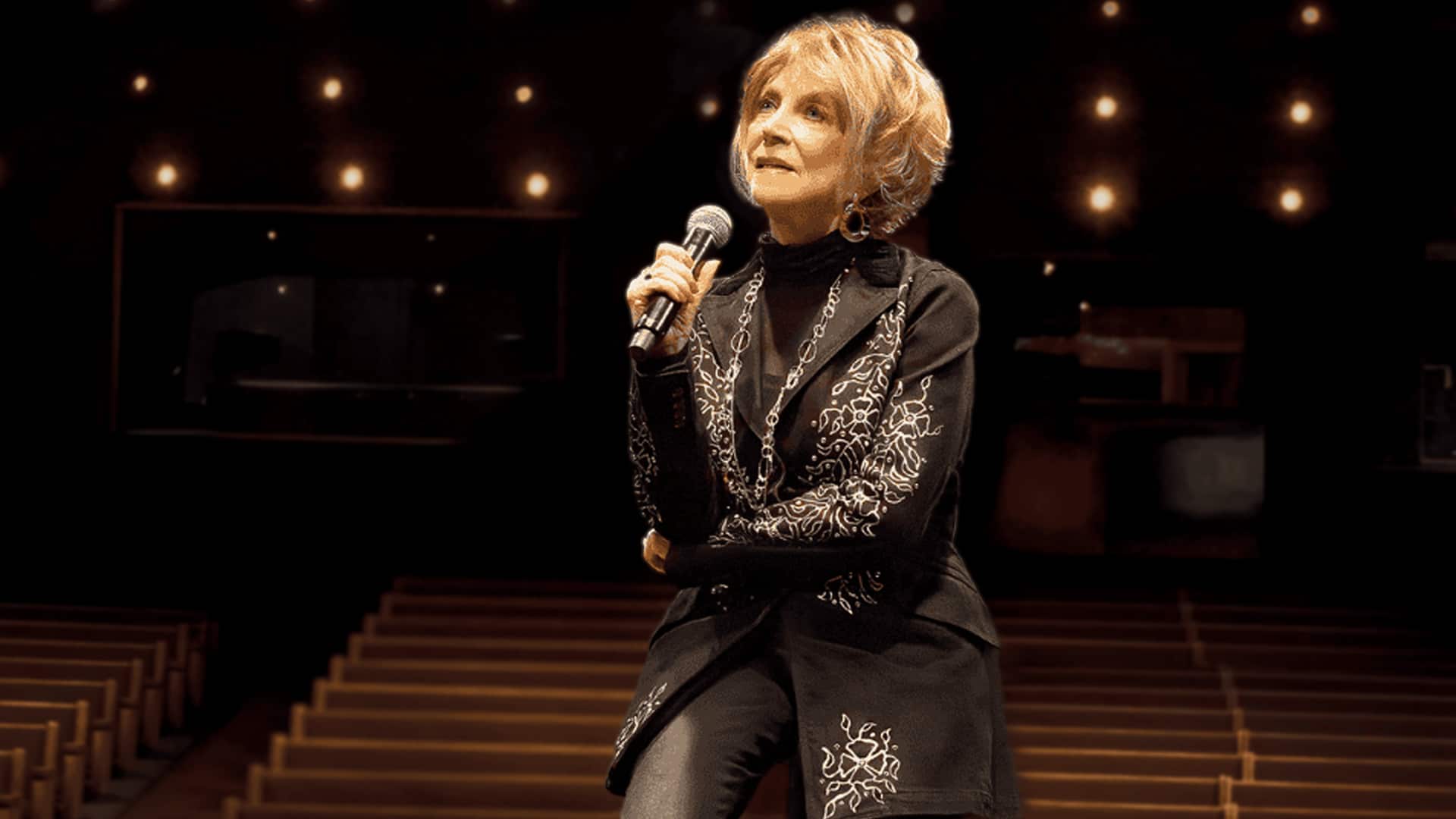 Jeannie Seely holds a microphone while seated on stage at the Grand Ole Opry, where a public memorial service will honor her 5,398th show.