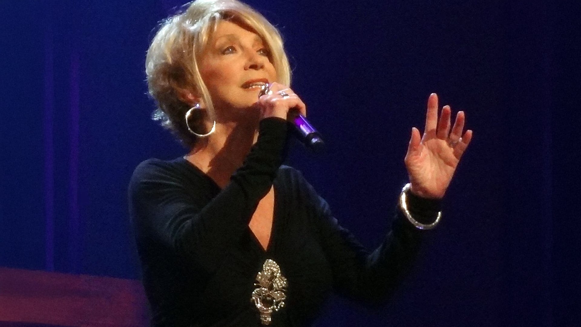 Jeannie Seely performs with heartfelt emotion on stage in this photo, now remembered after she passed away from an intestinal infection at 85.