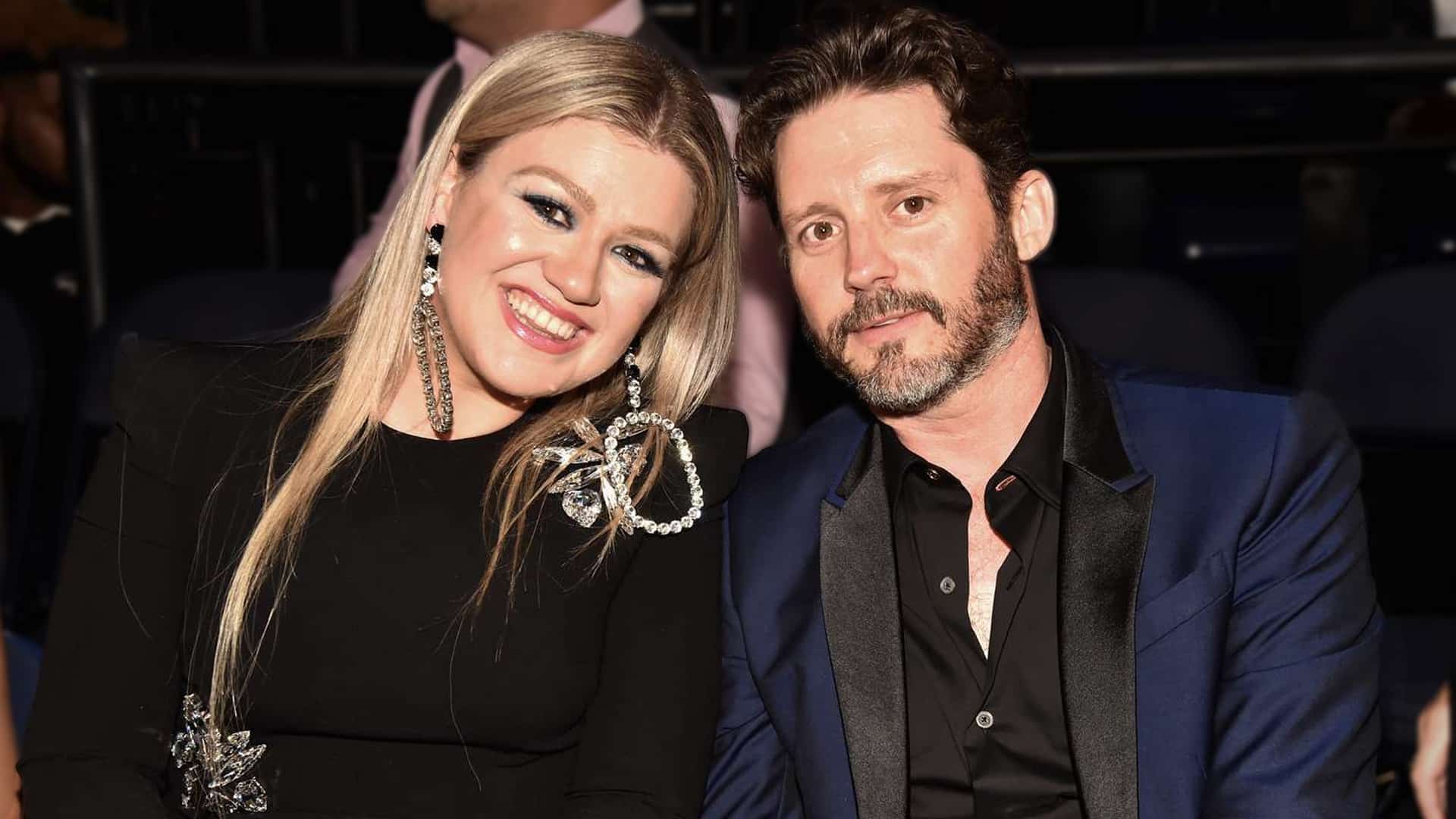 Kelly Clarkson smiles beside ex-husband Brandon Blackstock in a past public appearance, now mourning his passing while supporting their children.