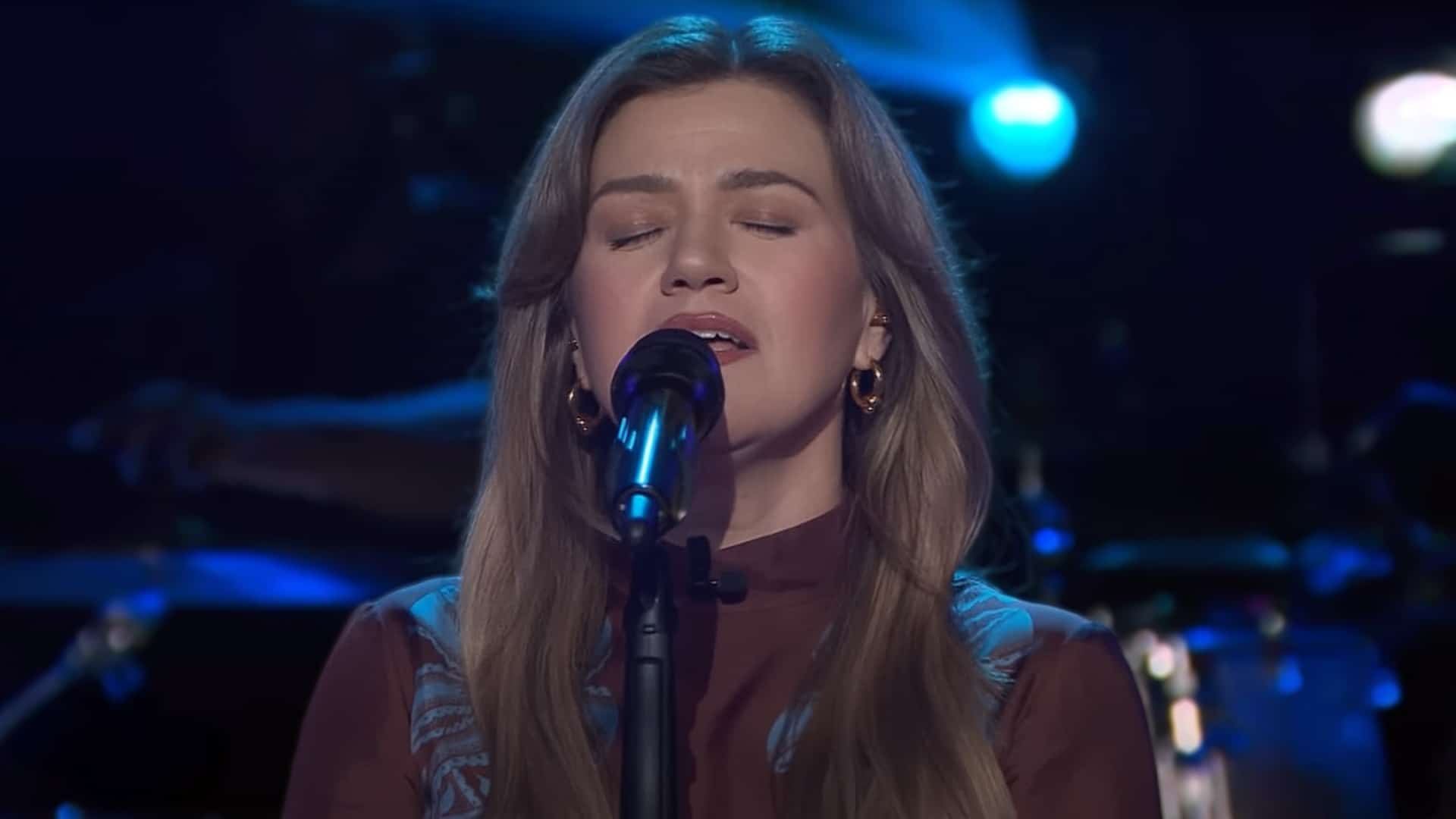 Kelly Clarkson singing on stage in a past performance, as news breaks of her decision to withdraw from a Texas benefit concert following ex-husband Brandon Blackstock’s death.