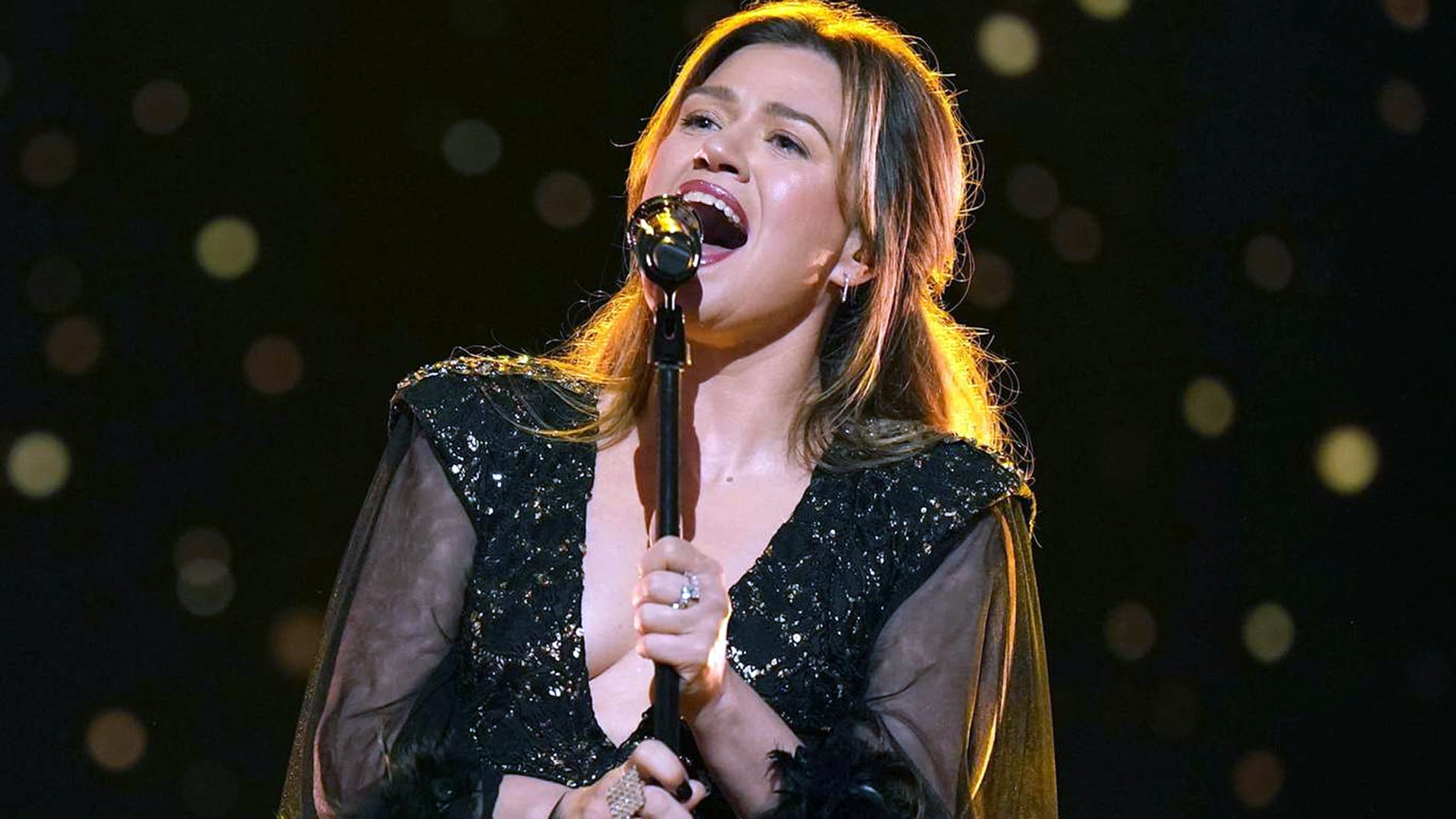Kelly Clarkson passionately performs on stage in a black sequined gown, recalling past remarks from then-husband Brandon Blackstock that she wasn’t “sexy” enough for 'The Voice.'