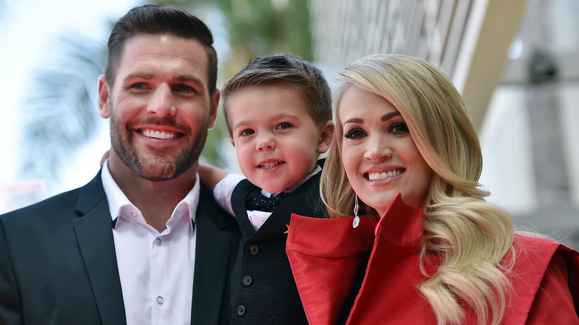Carrie Underwood smiles alongside husband Mike Fisher and their son Isaiah, offering a glimpse into the sweet family life behind her growing boys, Isaiah and Jacob.
