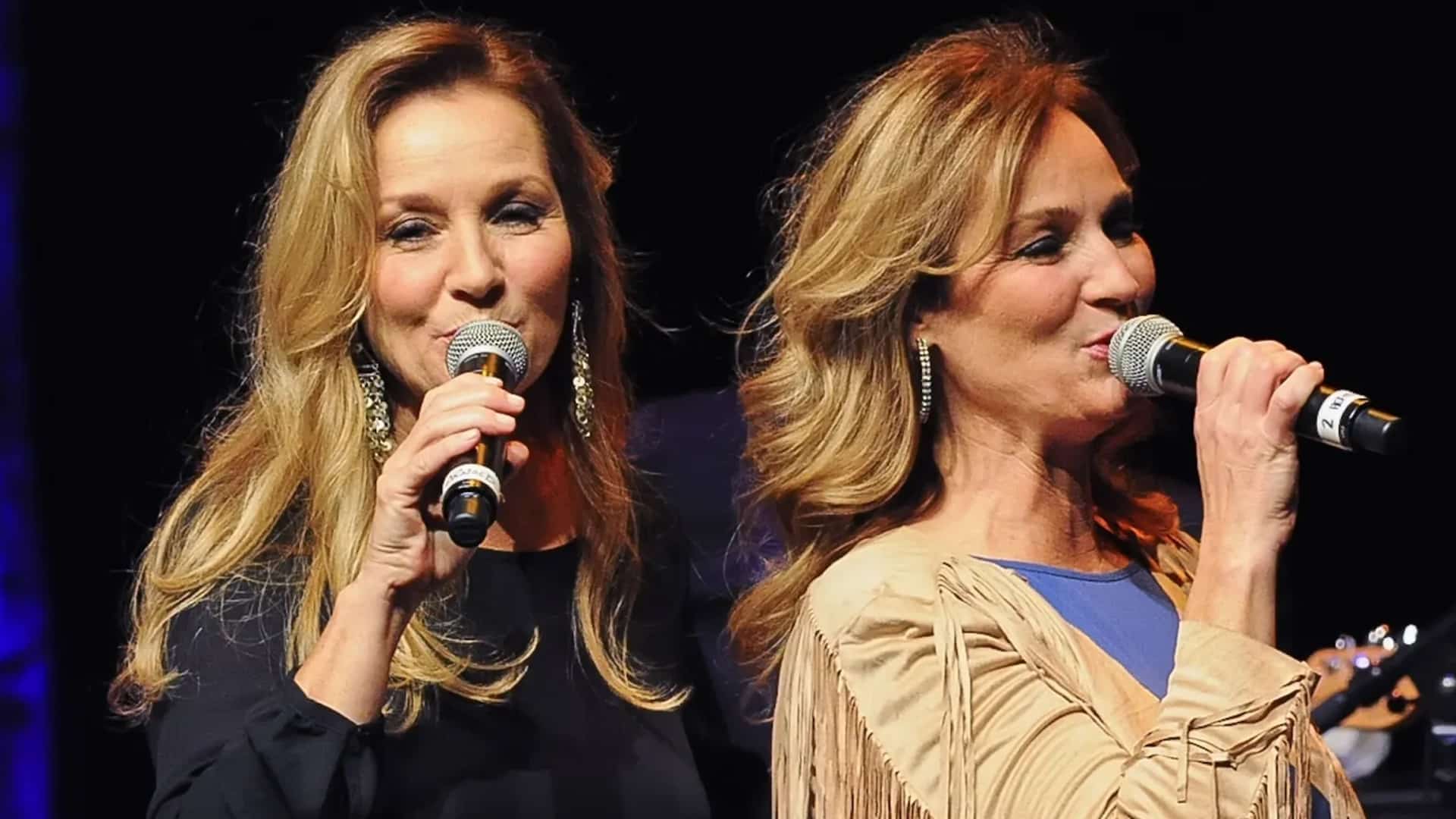 Loretta Lynn’s twin daughters, Peggy and Patsy, sing together on stage, carrying on the legacy of their legendary mother.