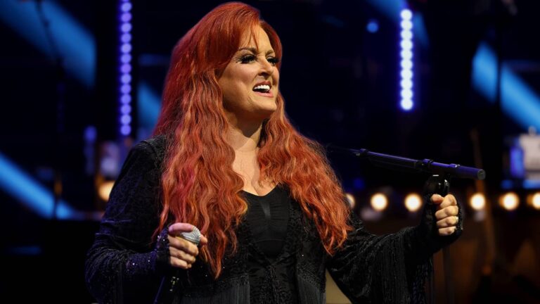 Country star Wynonna Judd singing under the stage lights, amid controversy over allegations raised by her daughter.