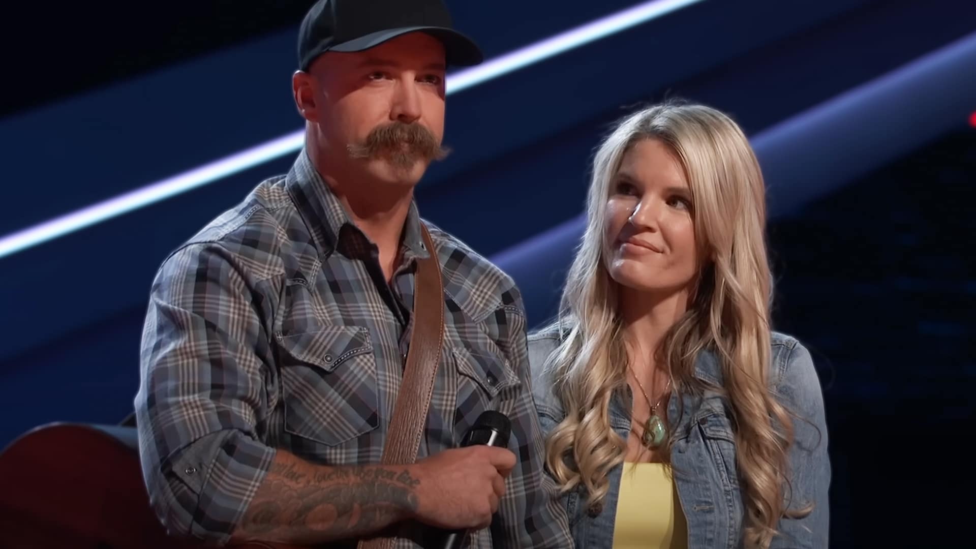 Firefighter Jacob Ryan Gustafson stands on The Voice stage with his fiancée after proposing following his Morgan Wallen audition.