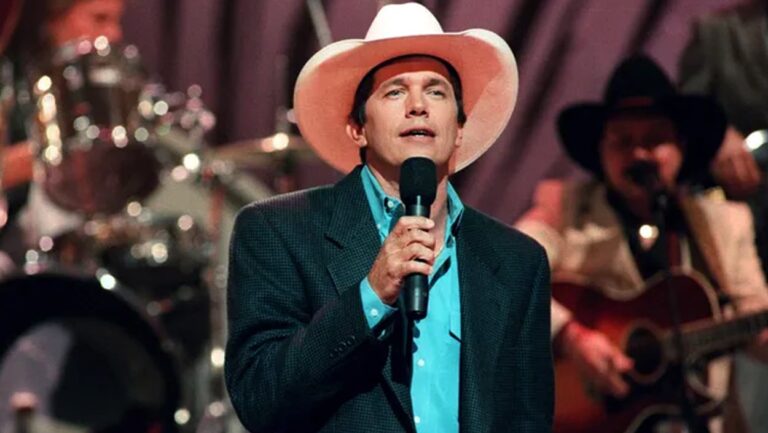 George Strait onstage with a microphone, proving Nashville wrong by saving a controversial lyric and making it a chart-topping classic.