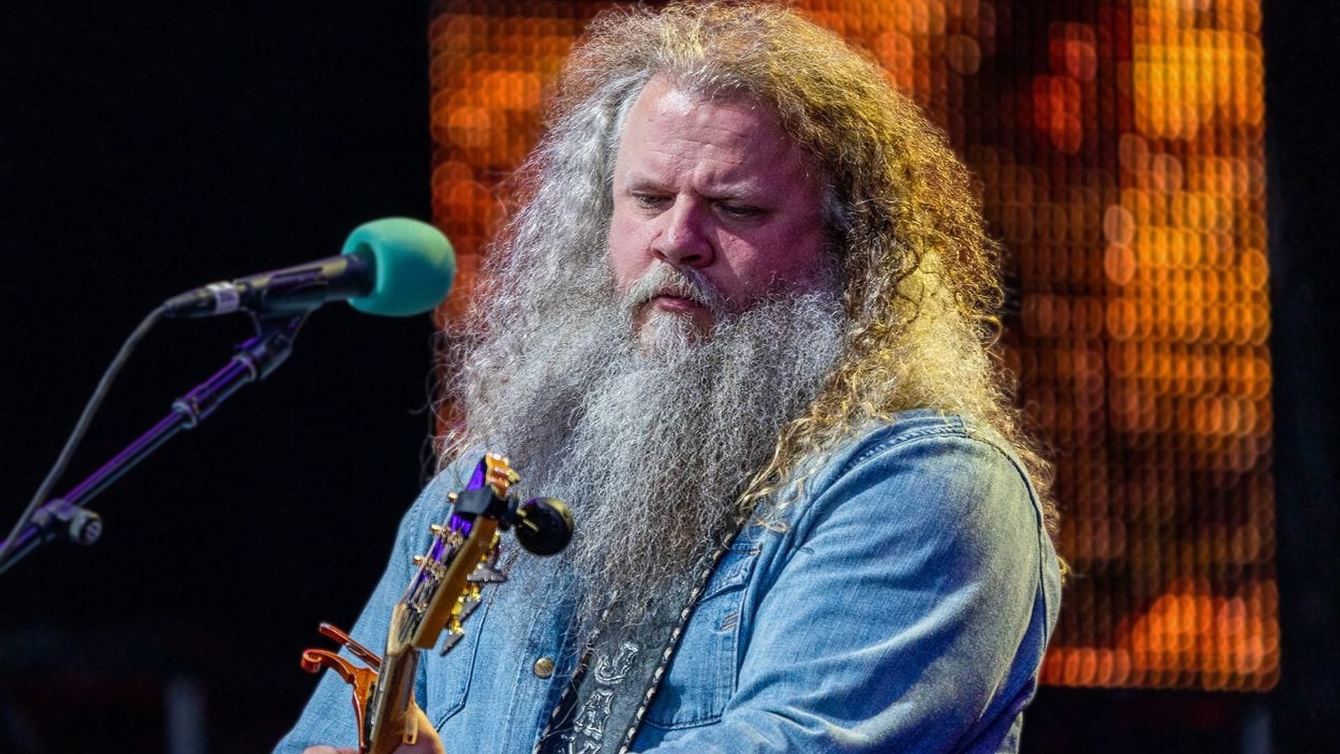Jamey Johnson performing onstage with guitar, speaking openly about listening to today’s country artists like Morgan Wallen.