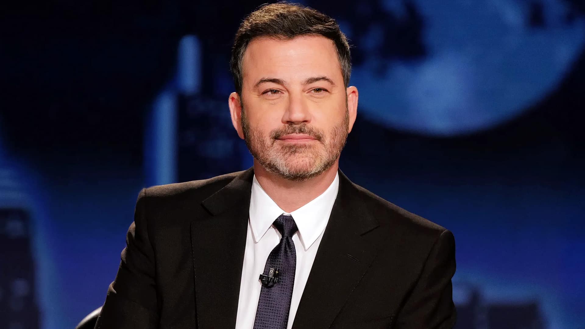 Jimmy Kimmel on set in a suit and tie, returning to late night with remarks about Erika Kirk’s powerful act of forgiveness.